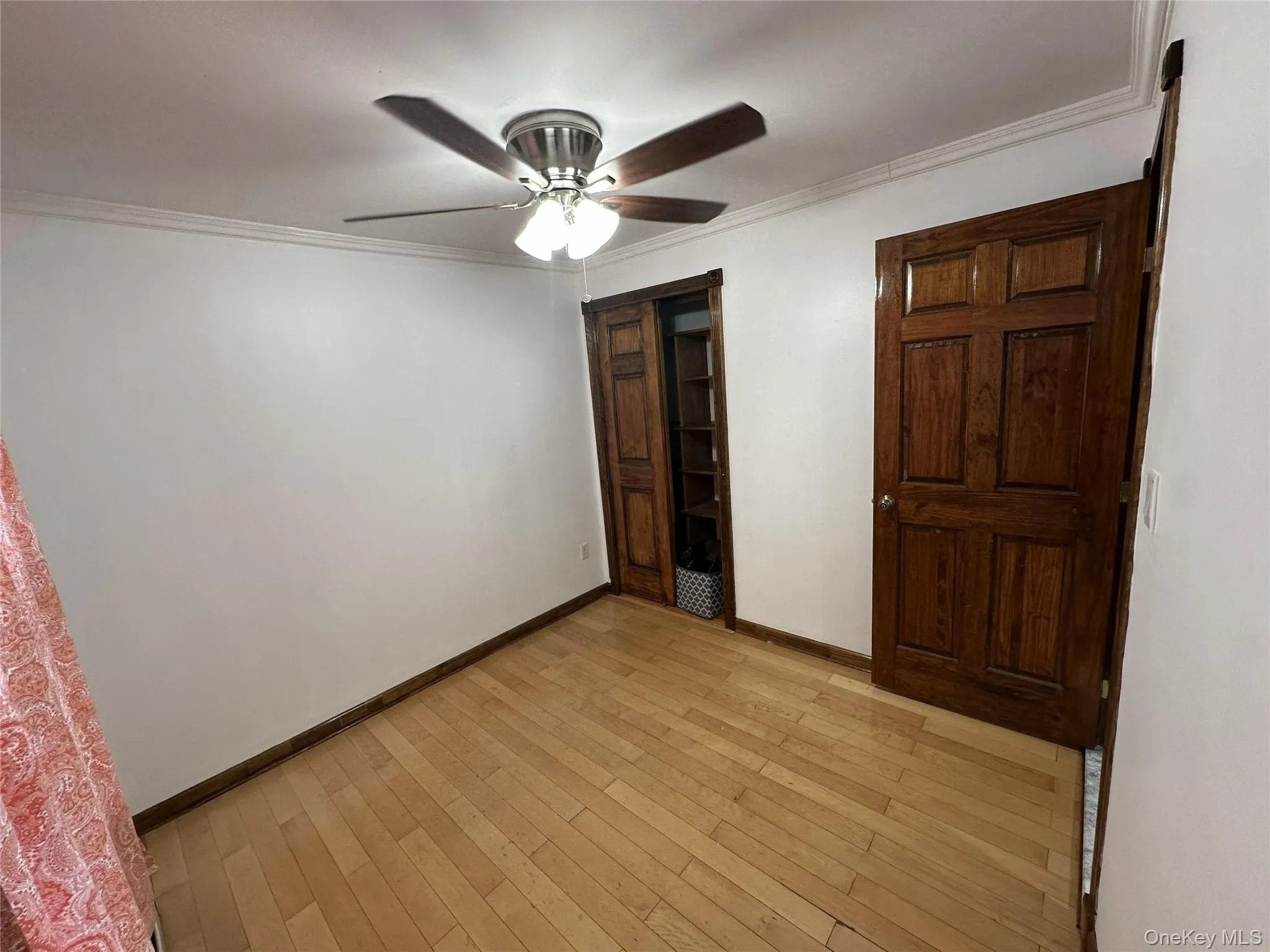 Unfurnished bedroom with crown molding, light wood-type flooring, and a ceiling fan Unfurnished bedroom with crown molding, light wood-type flooring, and a ceiling fan