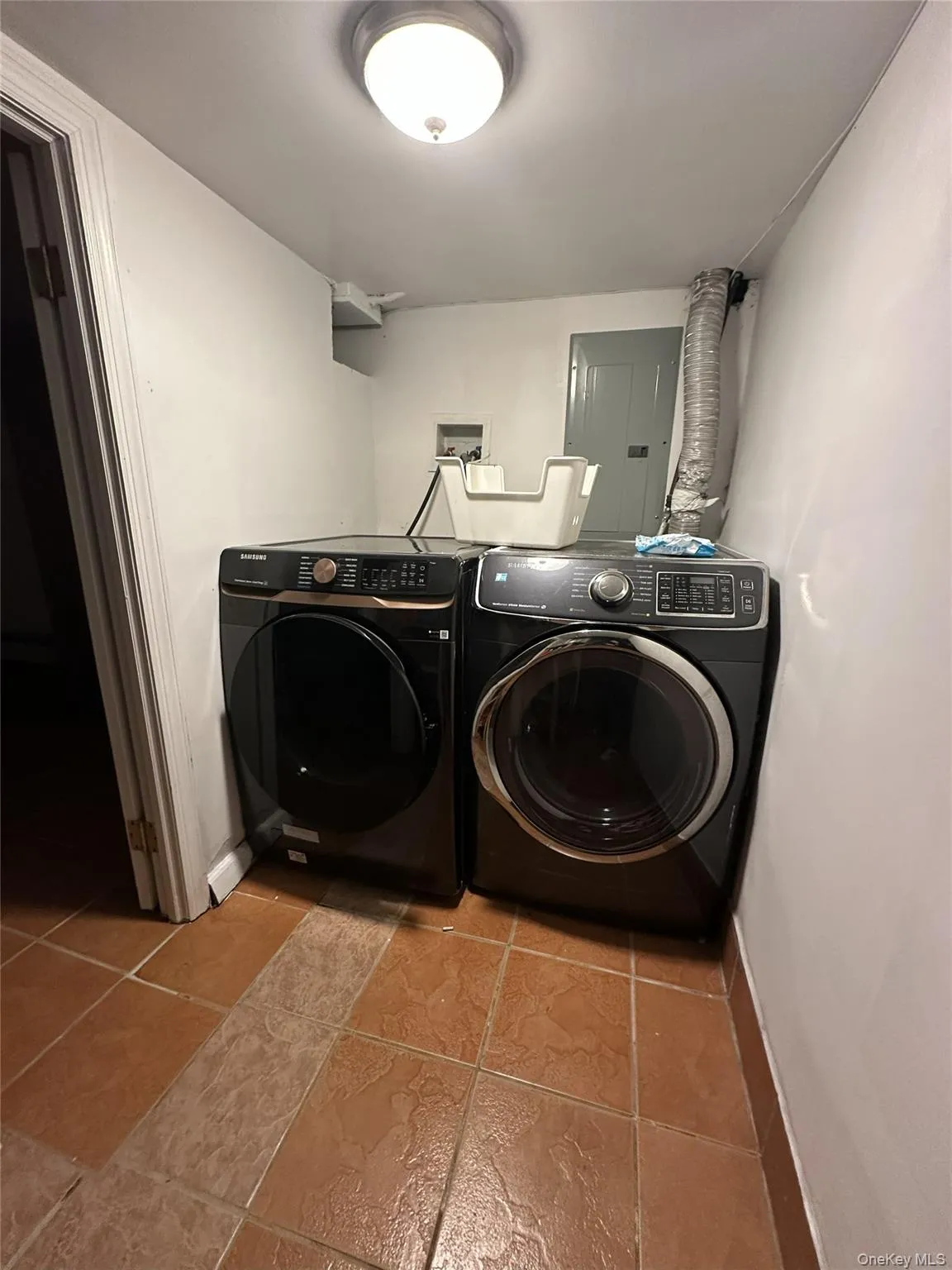 Laundry area featuring electric panel, independent washer and dryer, and tile patterned floors Laundry area featuring electric panel, independent washer and dryer, and tile patterned floors