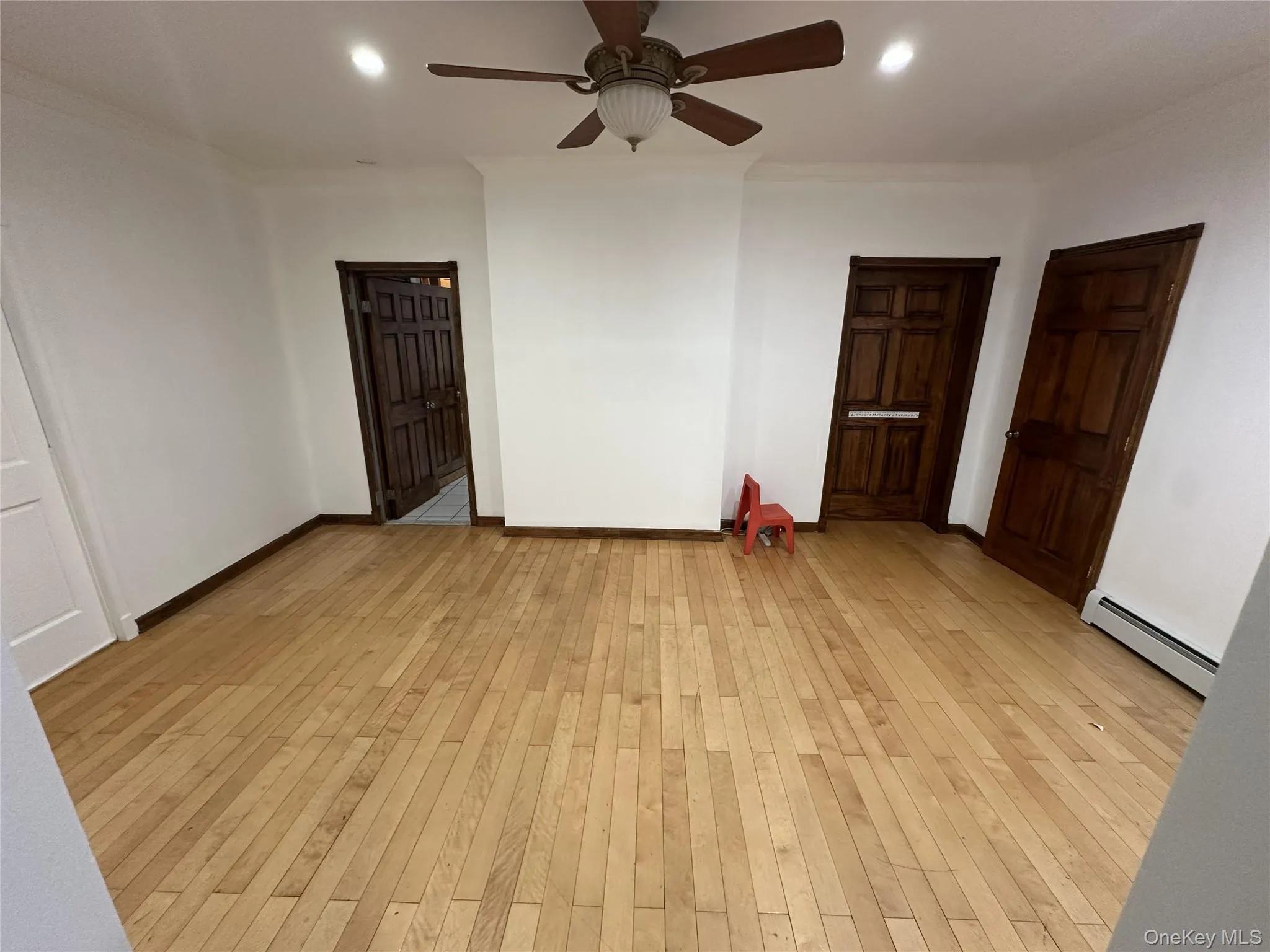 Empty room featuring light wood-style flooring, ornamental molding, baseboard heating, recessed lighting, and a ceiling fan Empty room featuring light wood-style flooring, ornamental molding, baseboard heating, recessed lighting, and a ceiling fan
