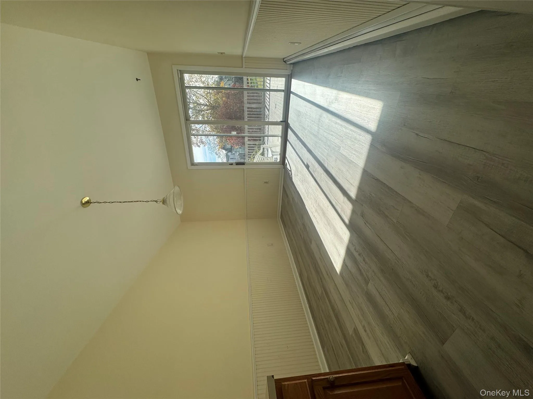 Empty room featuring a wainscoted wall, baseboard heating, dark wood-style flooring, and lofted ceiling Empty room featuring a wainscoted wall, baseboard heating, dark wood-style flooring, and lofted ceiling