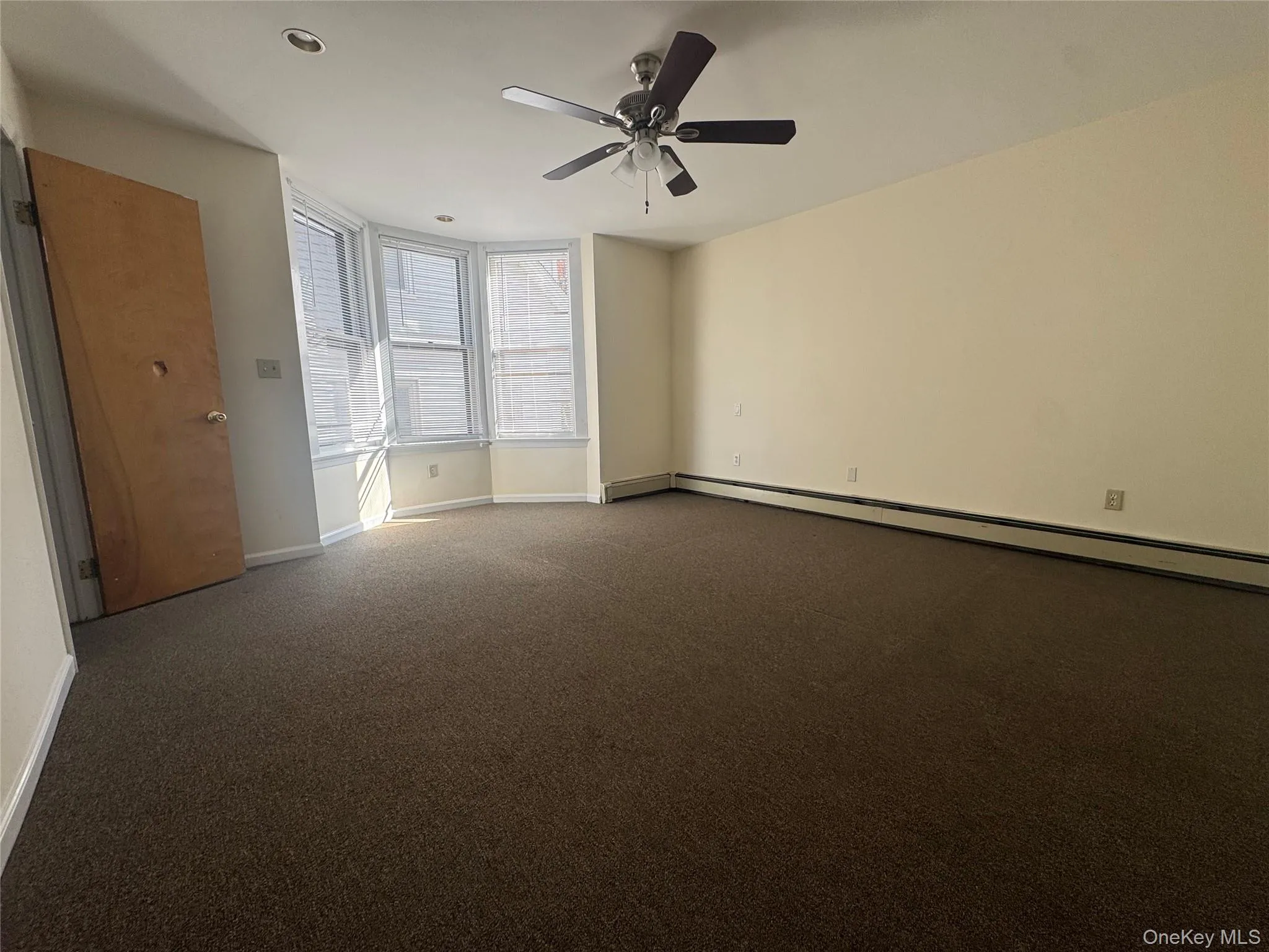 Unfurnished bedroom with carpet flooring, a ceiling fan, and baseboard heating Unfurnished bedroom with carpet flooring, a ceiling fan, and baseboard heating