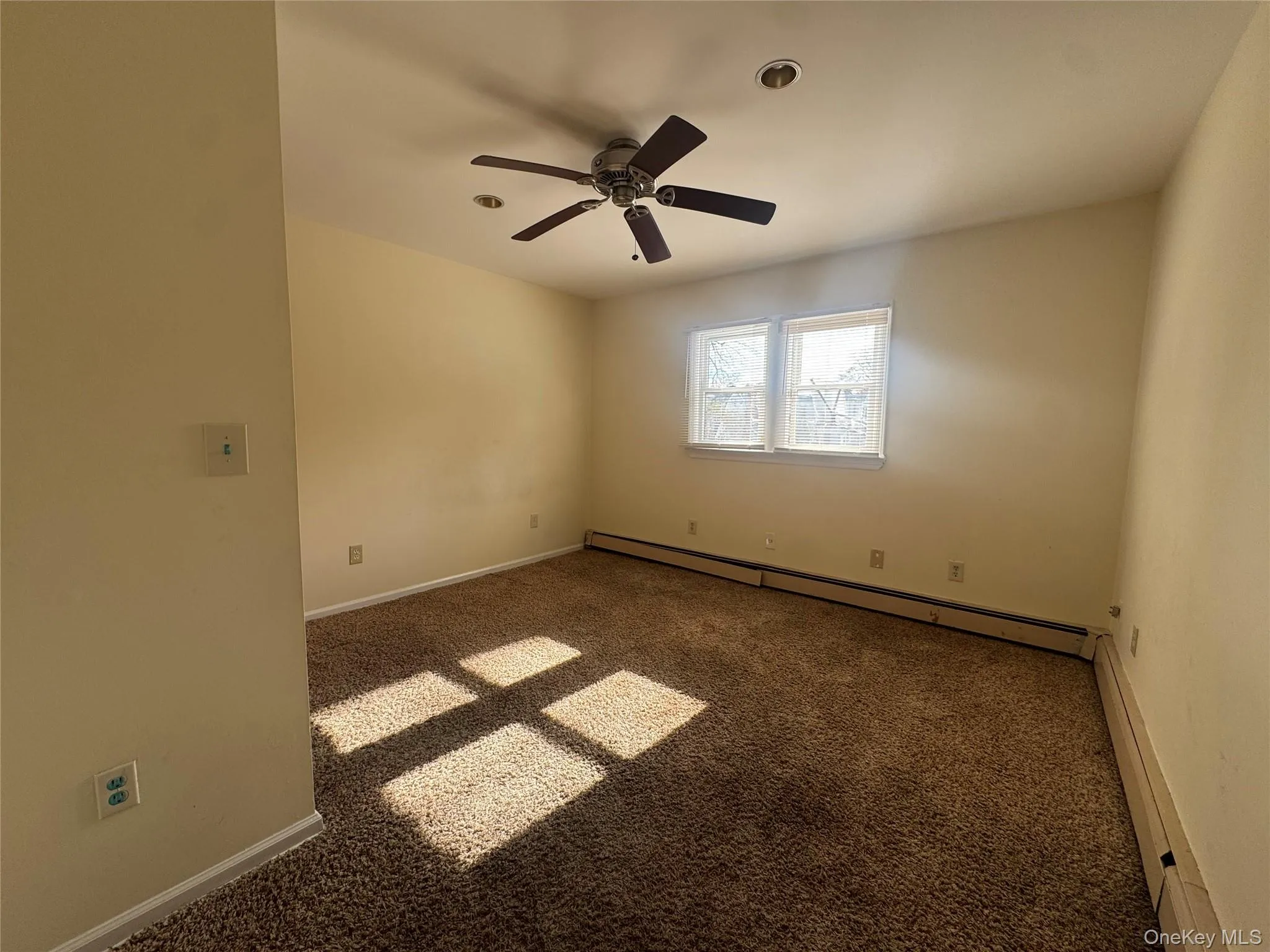Spare room with carpet, baseboard heating, a baseboard radiator, and a ceiling fan Spare room with carpet, baseboard heating, a baseboard radiator, and a ceiling fan