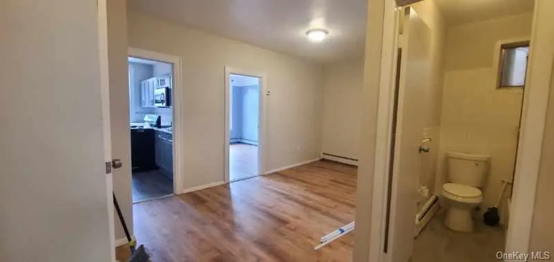 Hallway featuring wood finished floors and a baseboard heating unit Hallway featuring wood finished floors and a baseboard heating unit