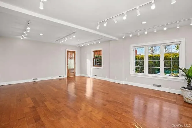 Unfurnished living room featuring wood finished floors and rail lighting Unfurnished living room featuring wood finished floors and rail lighting