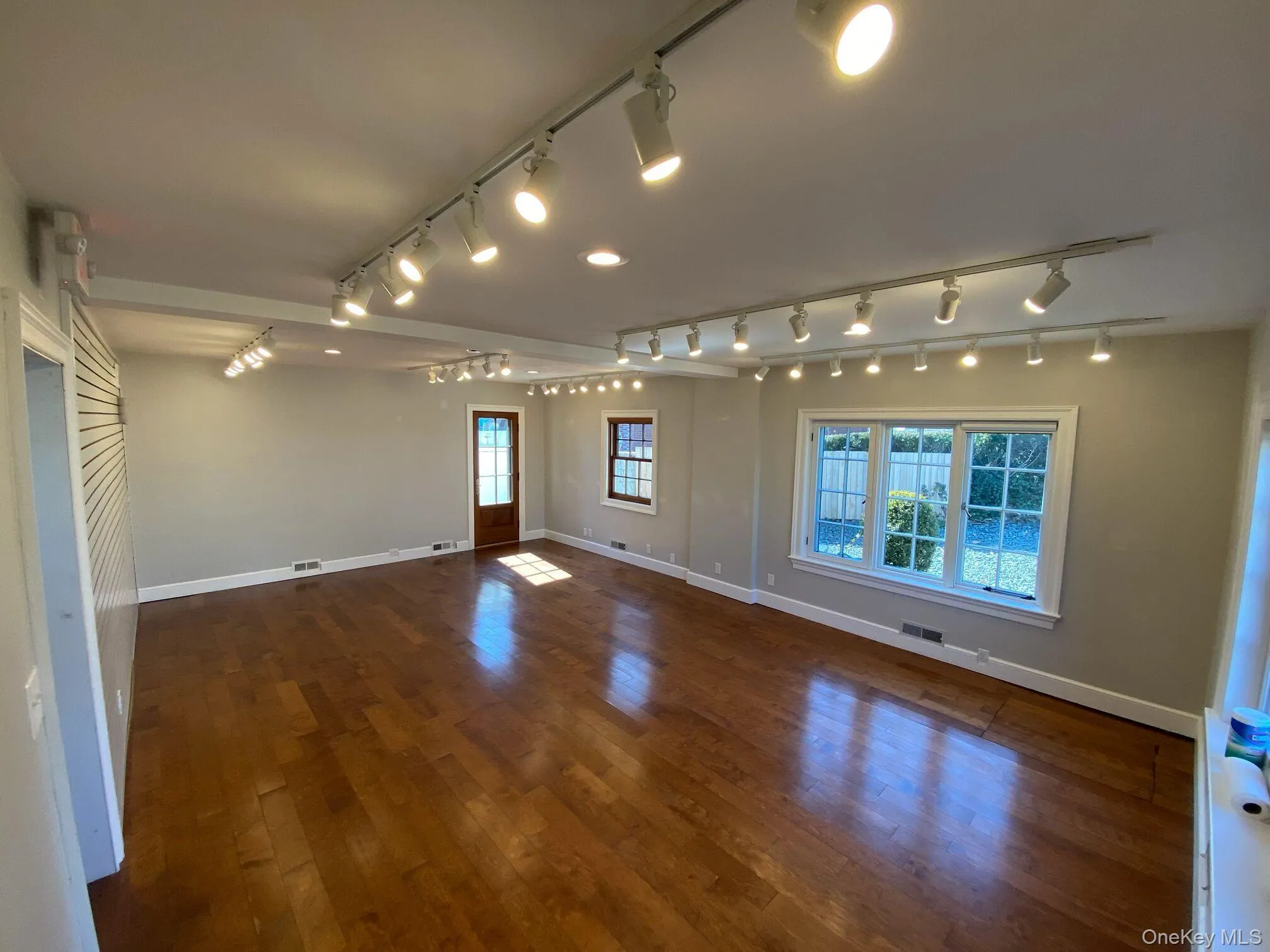 Spare room with track lighting, healthy amount of natural light, and dark wood-style flooring Spare room with track lighting, healthy amount of natural light, and dark wood-style flooring