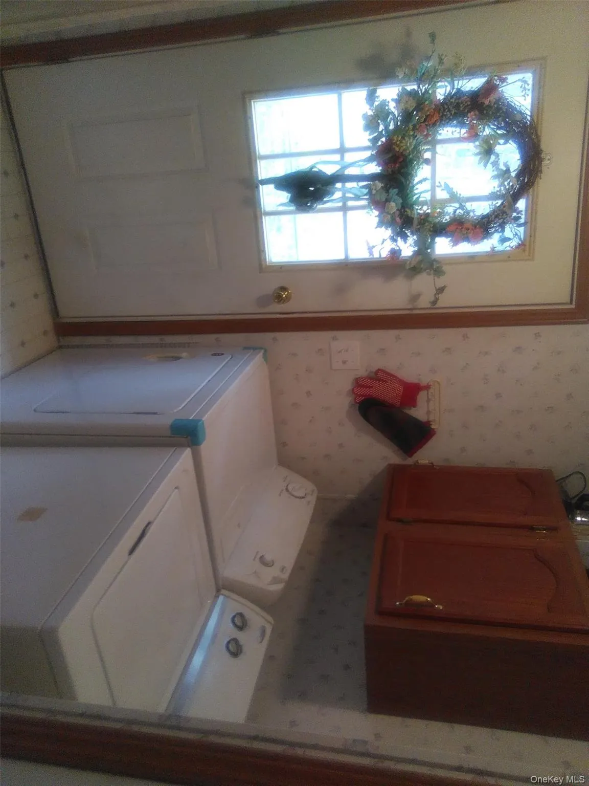 Washroom with cabinet space, wallpapered walls, separate washer and dryer, and light flooring Washroom with cabinet space, wallpapered walls, separate washer and dryer, and light flooring