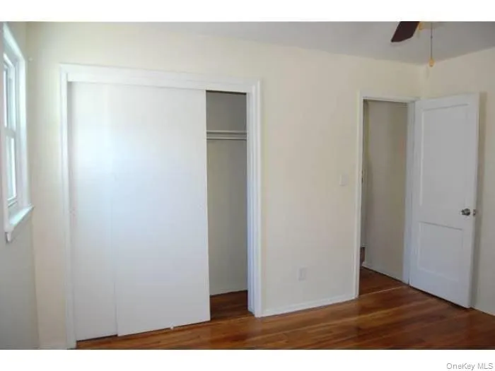Unfurnished bedroom featuring dark wood-style flooring, a closet, and a ceiling fan Unfurnished bedroom featuring dark wood-style flooring, a closet, and a ceiling fan