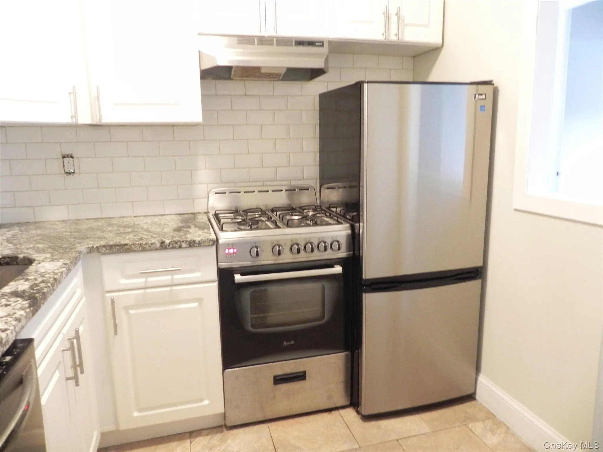 Kitchen featuring decorative backsplash, appliances with stainless steel finishes, and white cabinets Kitchen featuring decorative backsplash, appliances with stainless steel finishes, and white cabinets