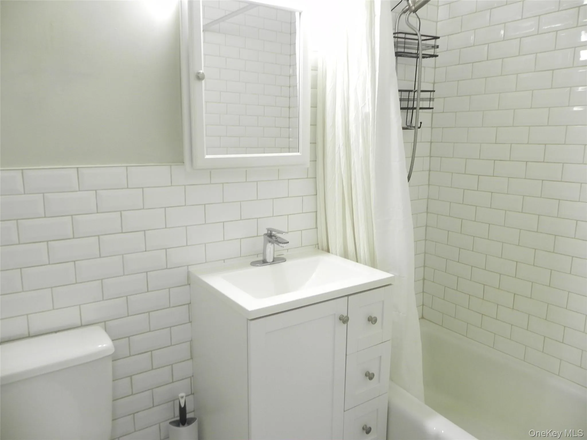 Full bathroom featuring vanity, toilet, tile walls, and shower / tub combo Full bathroom featuring vanity, toilet, tile walls, and shower / tub combo