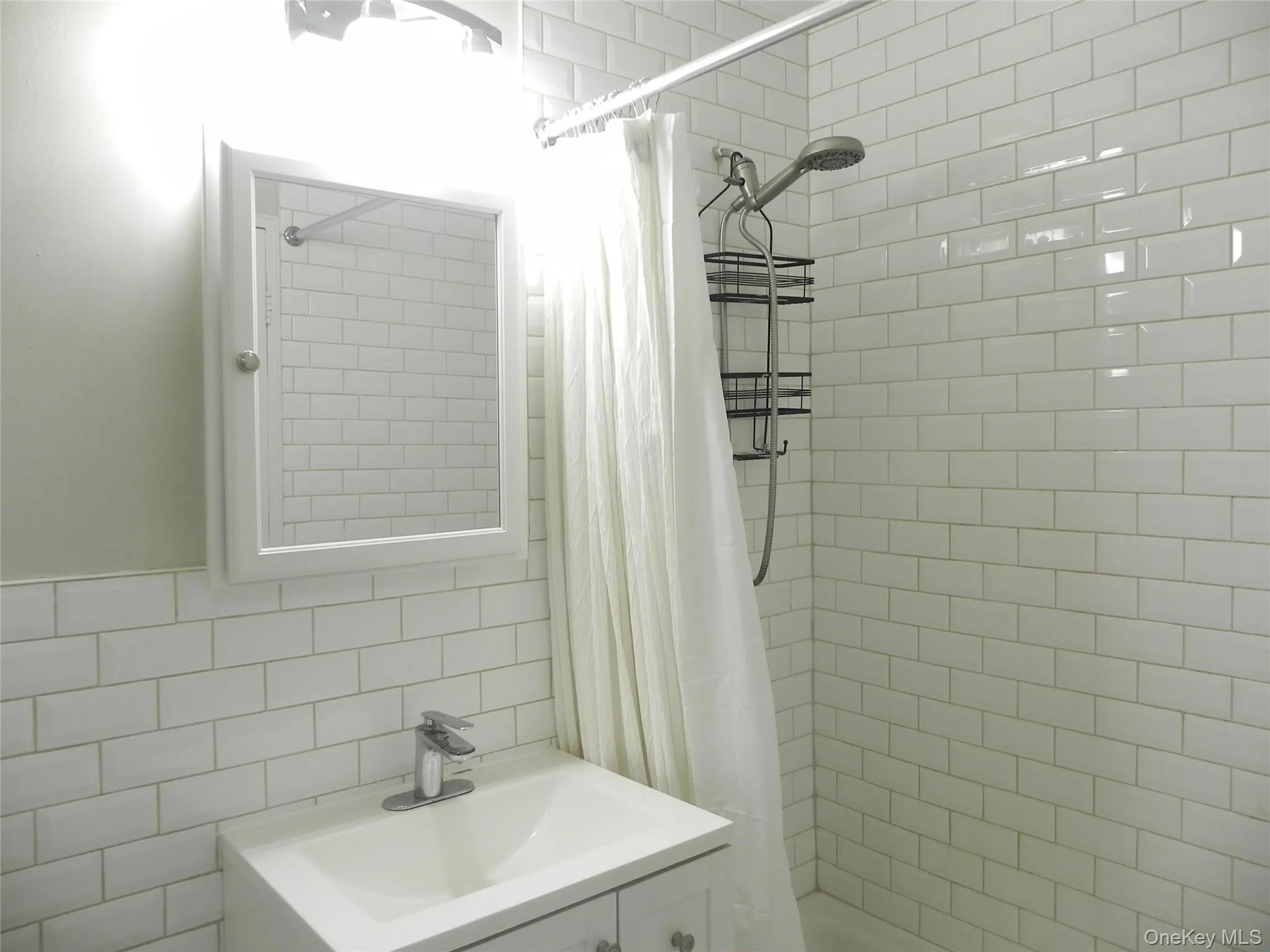 Bathroom with a shower with curtain, sink, and tile walls Bathroom with a shower with curtain, sink, and tile walls