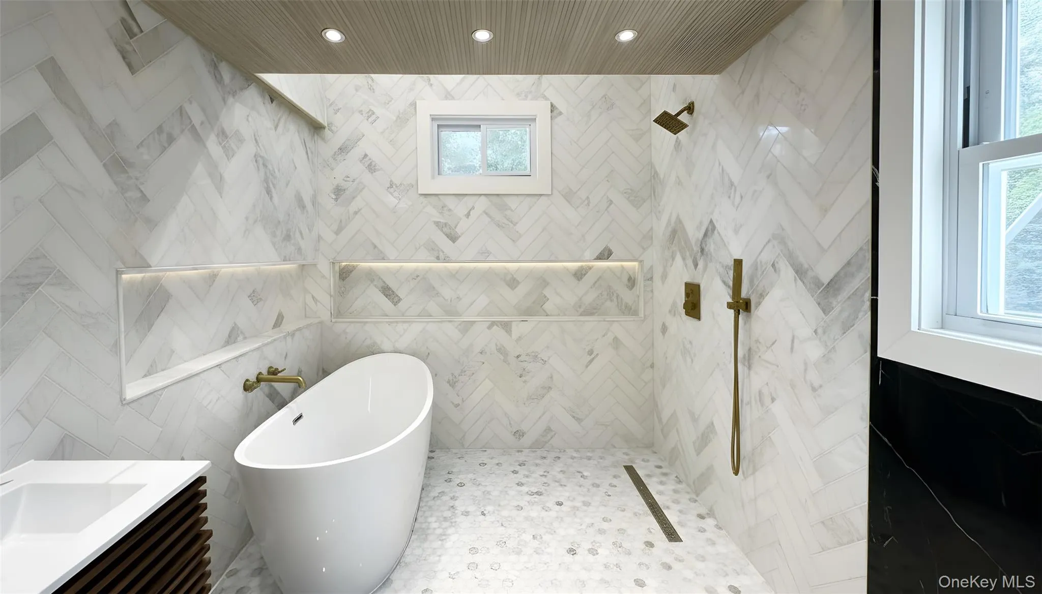 Bathroom with tile walls, a freestanding bath, vanity, recessed lighting, and tiled shower Bathroom with tile walls, a freestanding bath, vanity, recessed lighting, and tiled shower