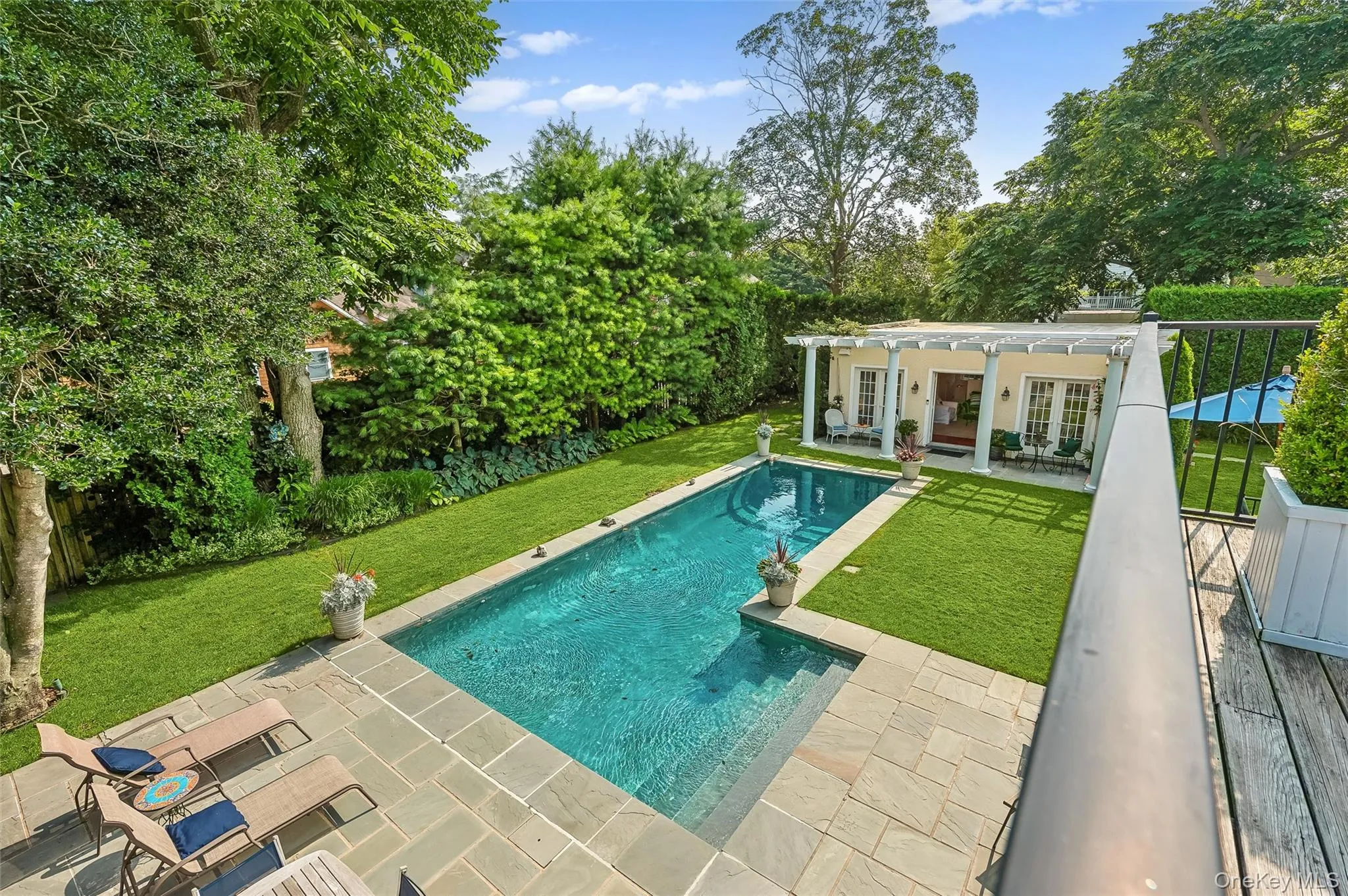 Outdoor pool featuring a yard, a patio area, french doors, an exterior structure, and view of wooded area Outdoor pool featuring a yard, a patio area, french doors, an exterior structure, and view of wooded area