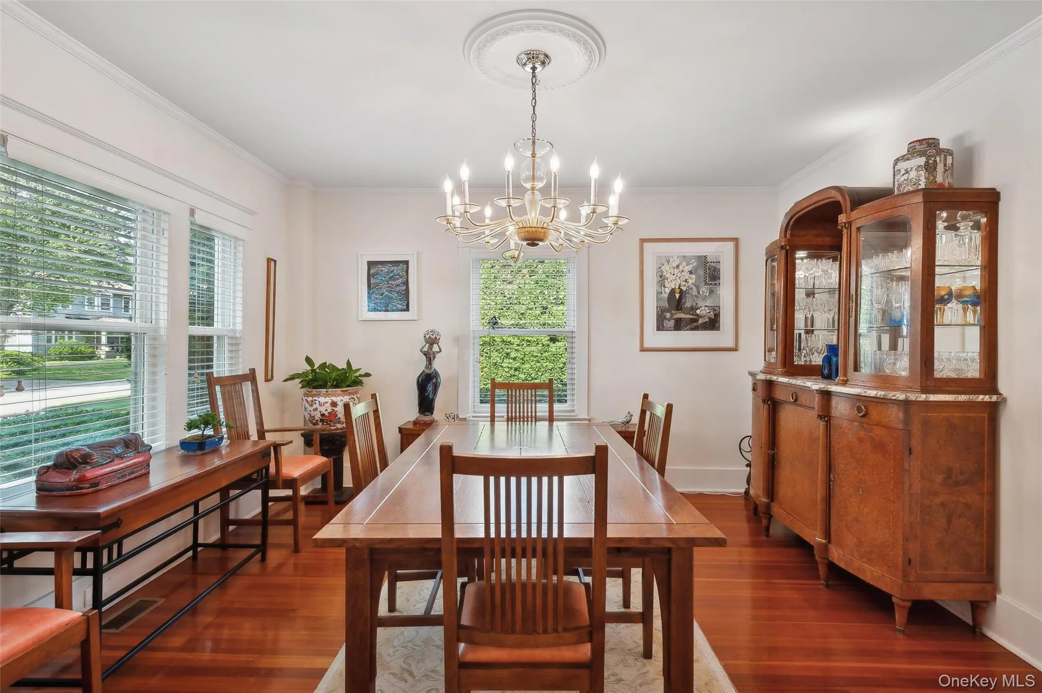 Dining area featuring dark wood-type flooring, healthy amount of natural light, crown molding, and a chandelier Dining area featuring dark wood-type flooring, healthy amount of natural light, crown molding, and a chandelier