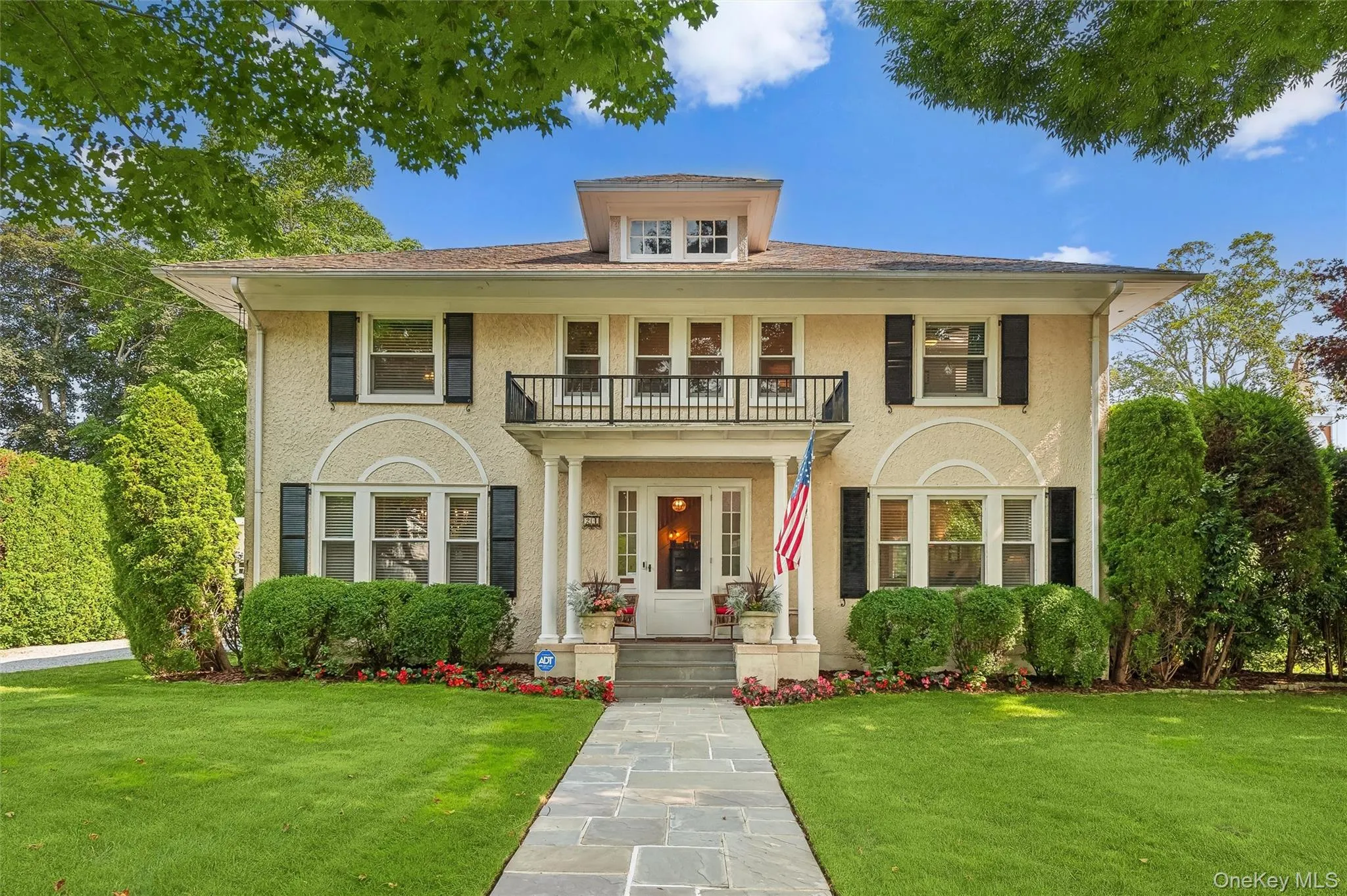 Colonial-style house with a front yard, stucco siding, and a balcony Colonial-style house with a front yard, stucco siding, and a balcony