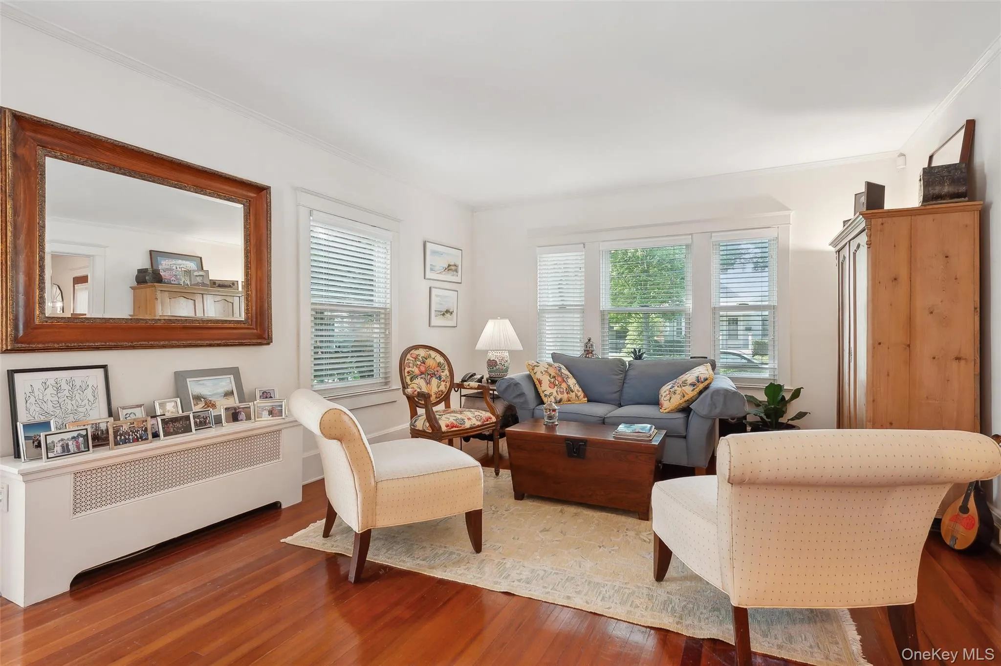Living area featuring wood finished floors, ornamental molding, and radiator heating unit Living area featuring wood finished floors, ornamental molding, and radiator heating unit