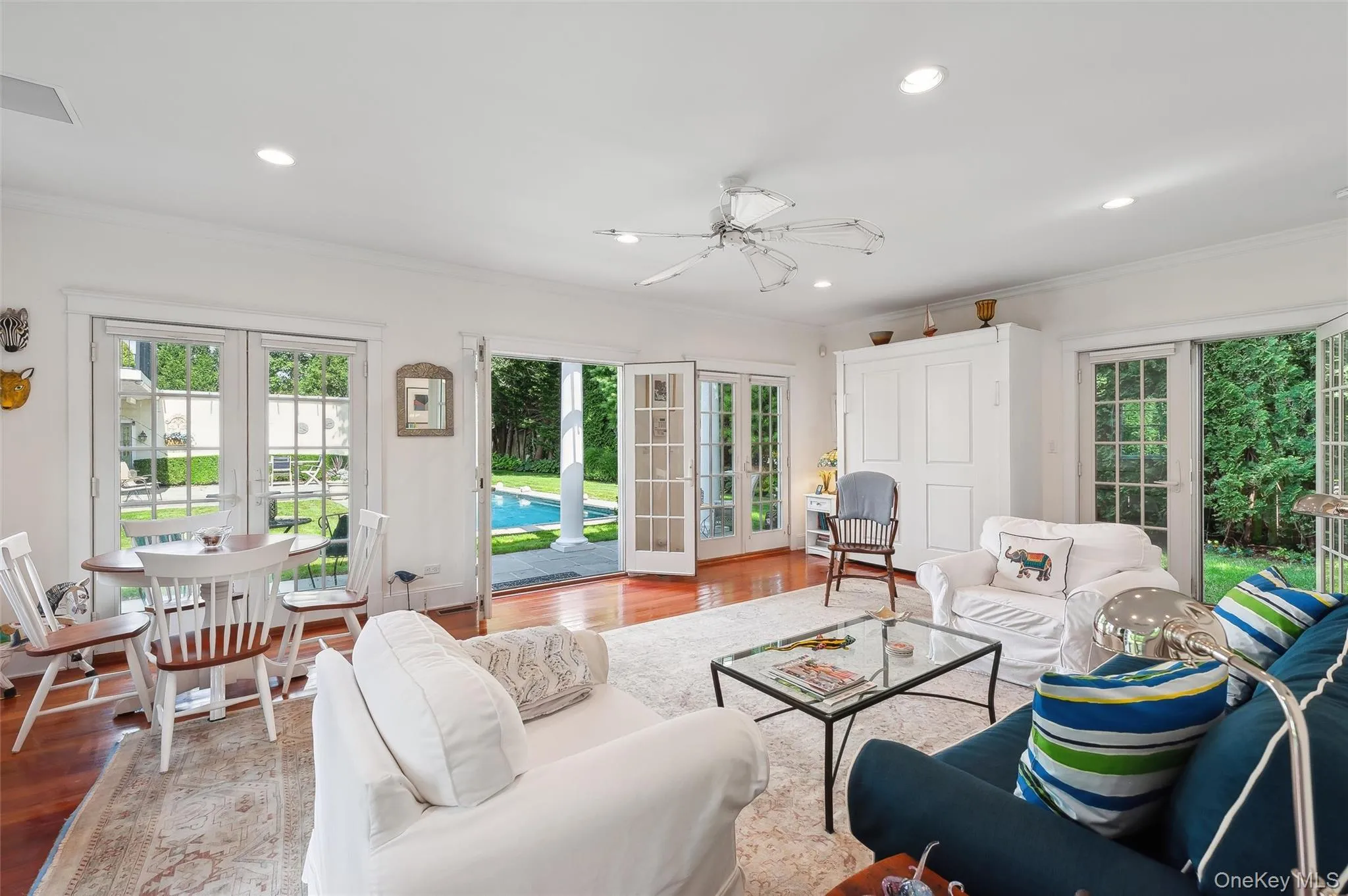 Living area with french doors, wood finished floors, ornamental molding, plenty of natural light, and recessed lighting Living area with french doors, wood finished floors, ornamental molding, plenty of natural light, and recessed lighting