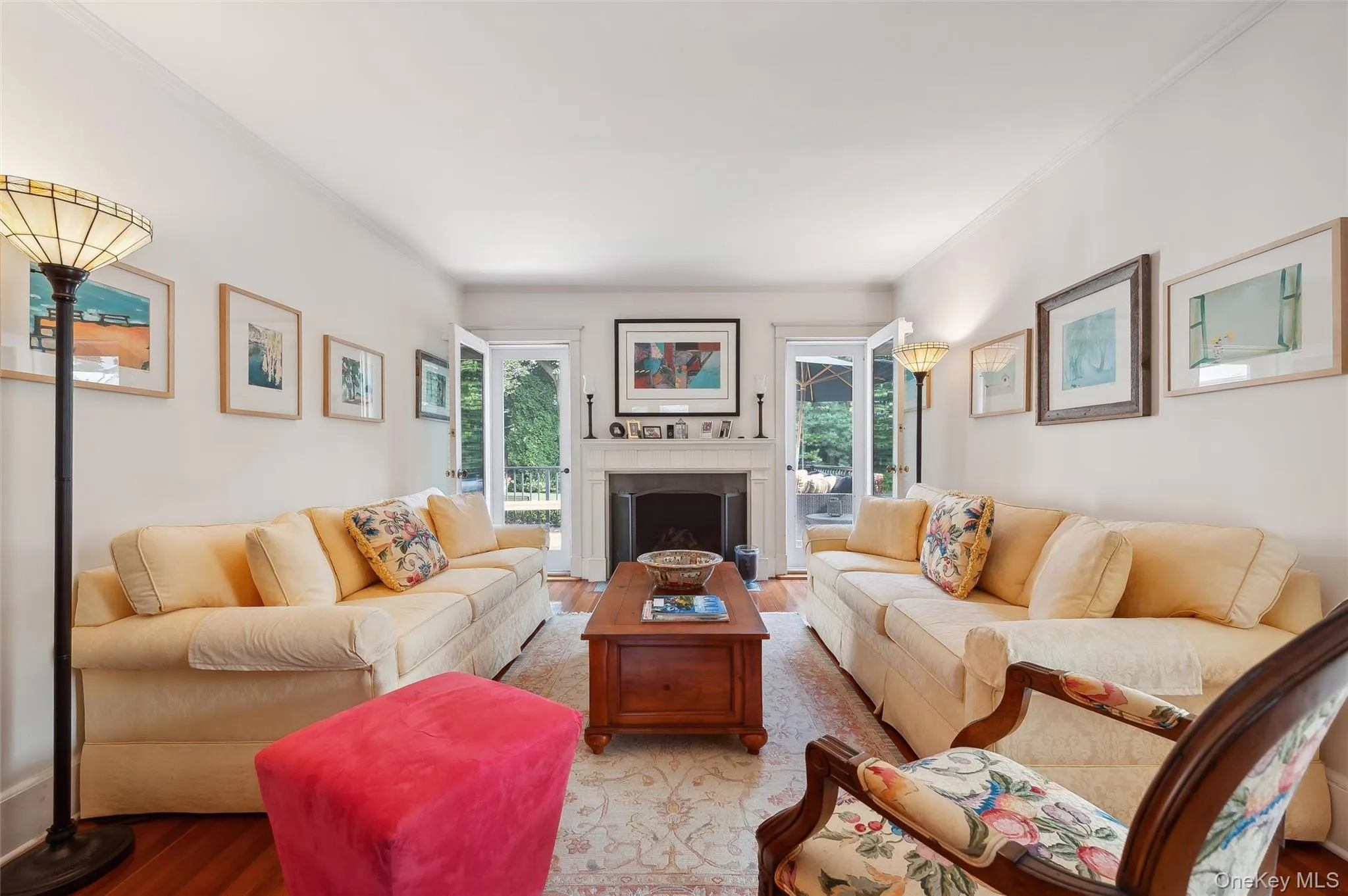 Living room with a fireplace, wood finished floors, healthy amount of natural light, and crown molding Living room with a fireplace, wood finished floors, healthy amount of natural light, and crown molding