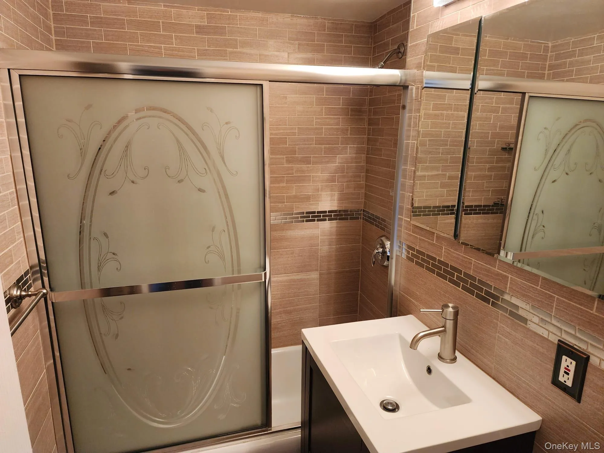 Bathroom with vanity, tile walls, combined bath / shower with glass door, and tasteful backsplash Bathroom with vanity, tile walls, combined bath / shower with glass door, and tasteful backsplash