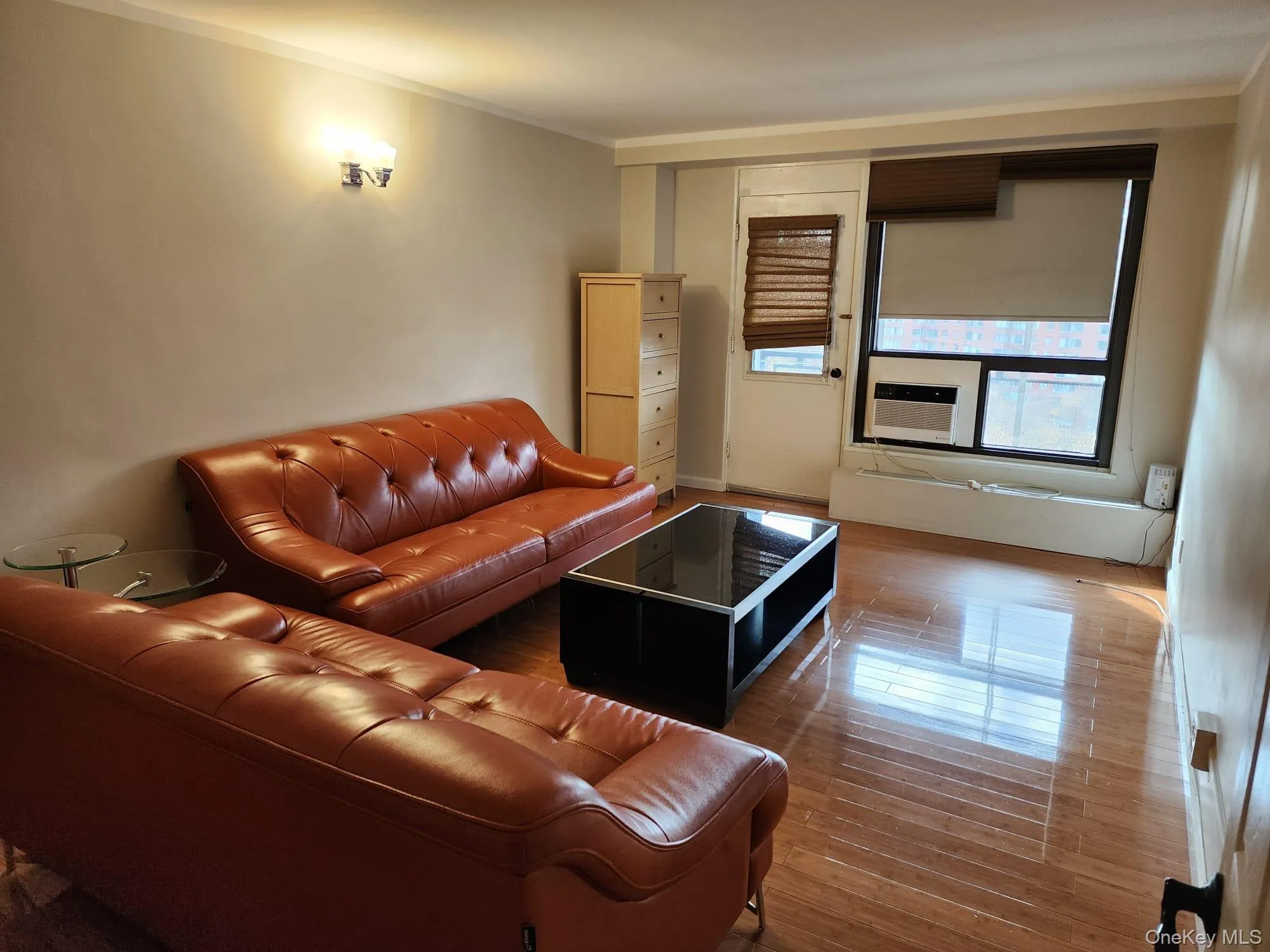 Living room featuring ornamental molding, wood finished floors, and cooling unit Living room featuring ornamental molding, wood finished floors, and cooling unit