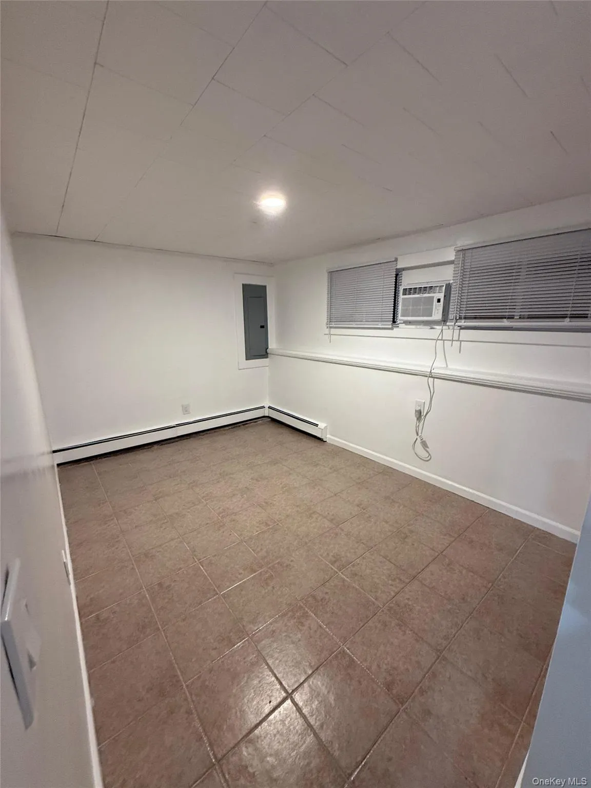 Finished basement with a baseboard heating unit and tile patterned flooring Finished basement with a baseboard heating unit and tile patterned flooring