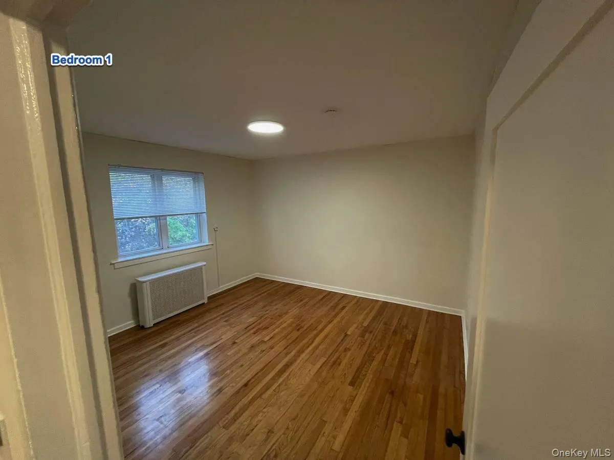 Spare room with wood finished floors and radiator Spare room with wood finished floors and radiator