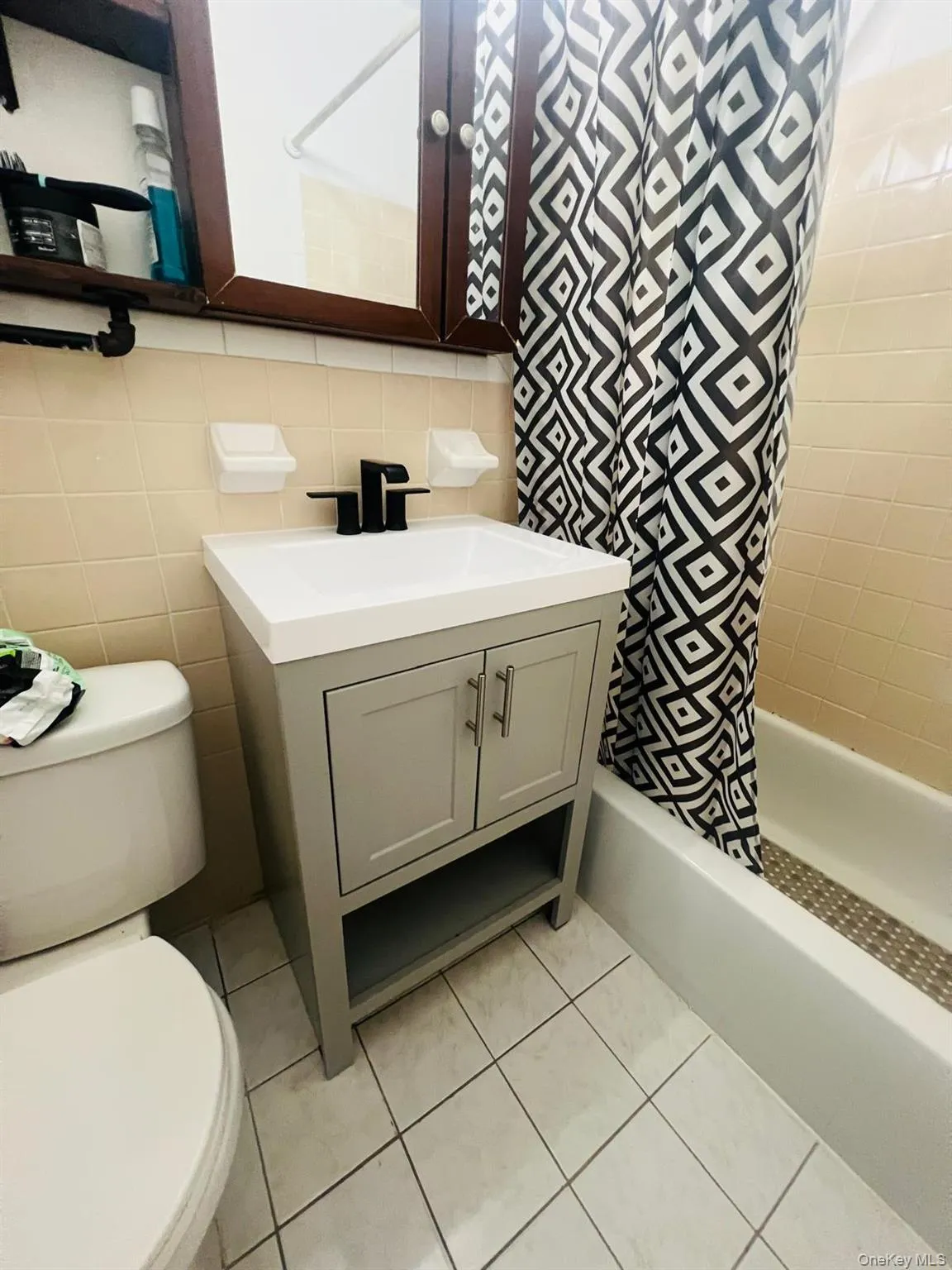 Full bath featuring vanity, tile walls, bathing tub / shower combination, light tile patterned flooring, and tasteful backsplash Full bath featuring vanity, tile walls, bathing tub / shower combination, light tile patterned flooring, and tasteful backsplash