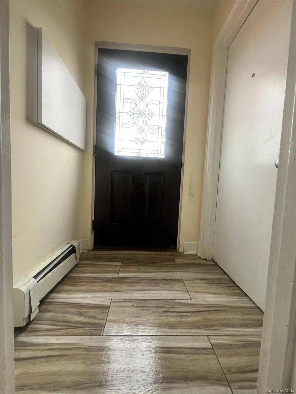 Doorway to outside with wood finished floors and baseboard heating Doorway to outside with wood finished floors and baseboard heating