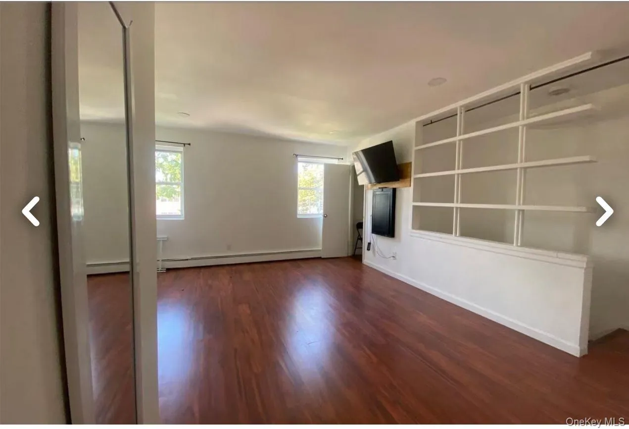 Unfurnished living room with dark wood-style floors and a baseboard heating unit Unfurnished living room with dark wood-style floors and a baseboard heating unit