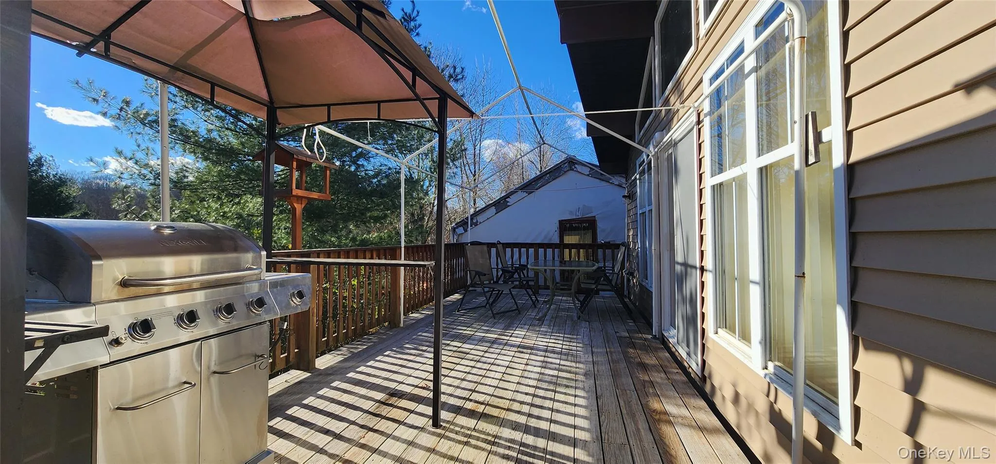Wooden deck with a grill and outdoor dining space Wooden deck with a grill and outdoor dining space