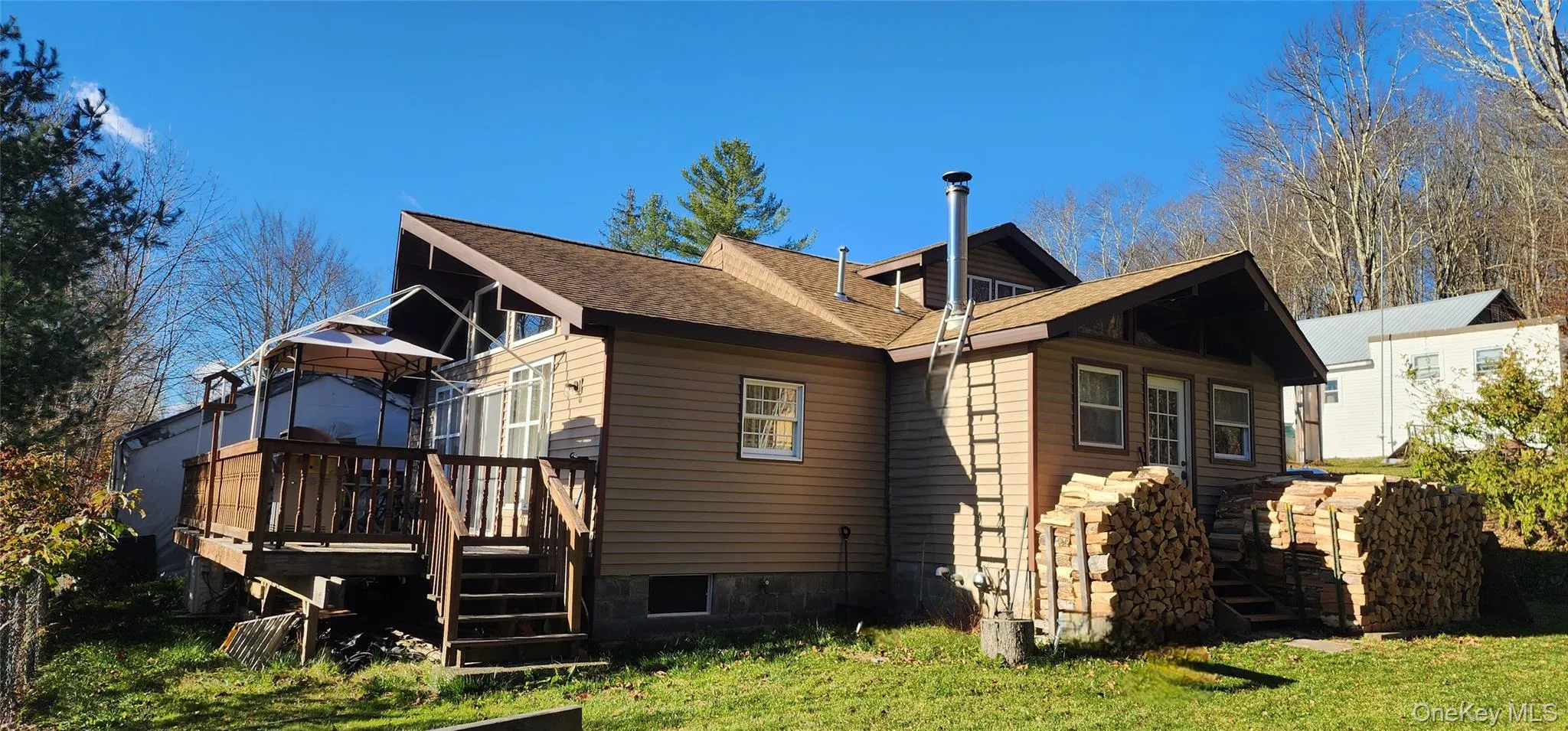 Rear view of house featuring stairs, roof with shingles, a deck, and a yard Rear view of house featuring stairs, roof with shingles, a deck, and a yard
