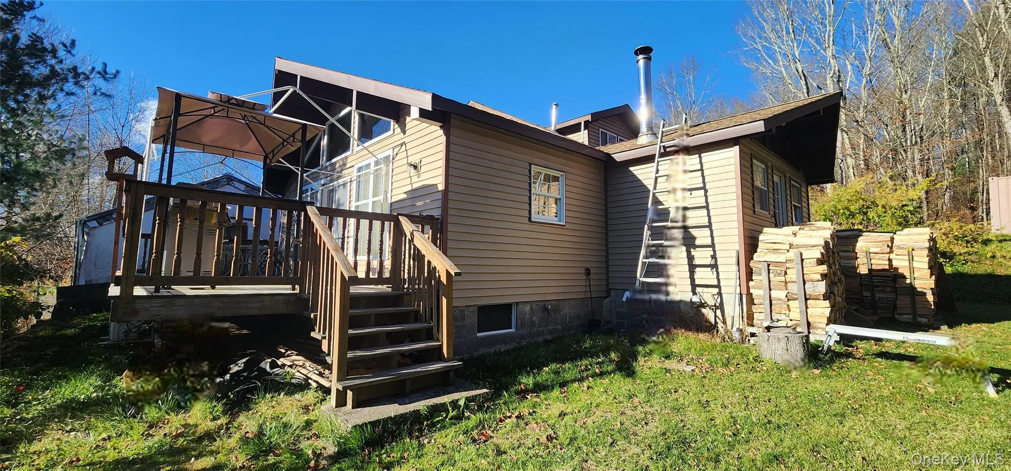 Back of property with a wooden deck, a lawn, and stairway Back of property with a wooden deck, a lawn, and stairway
