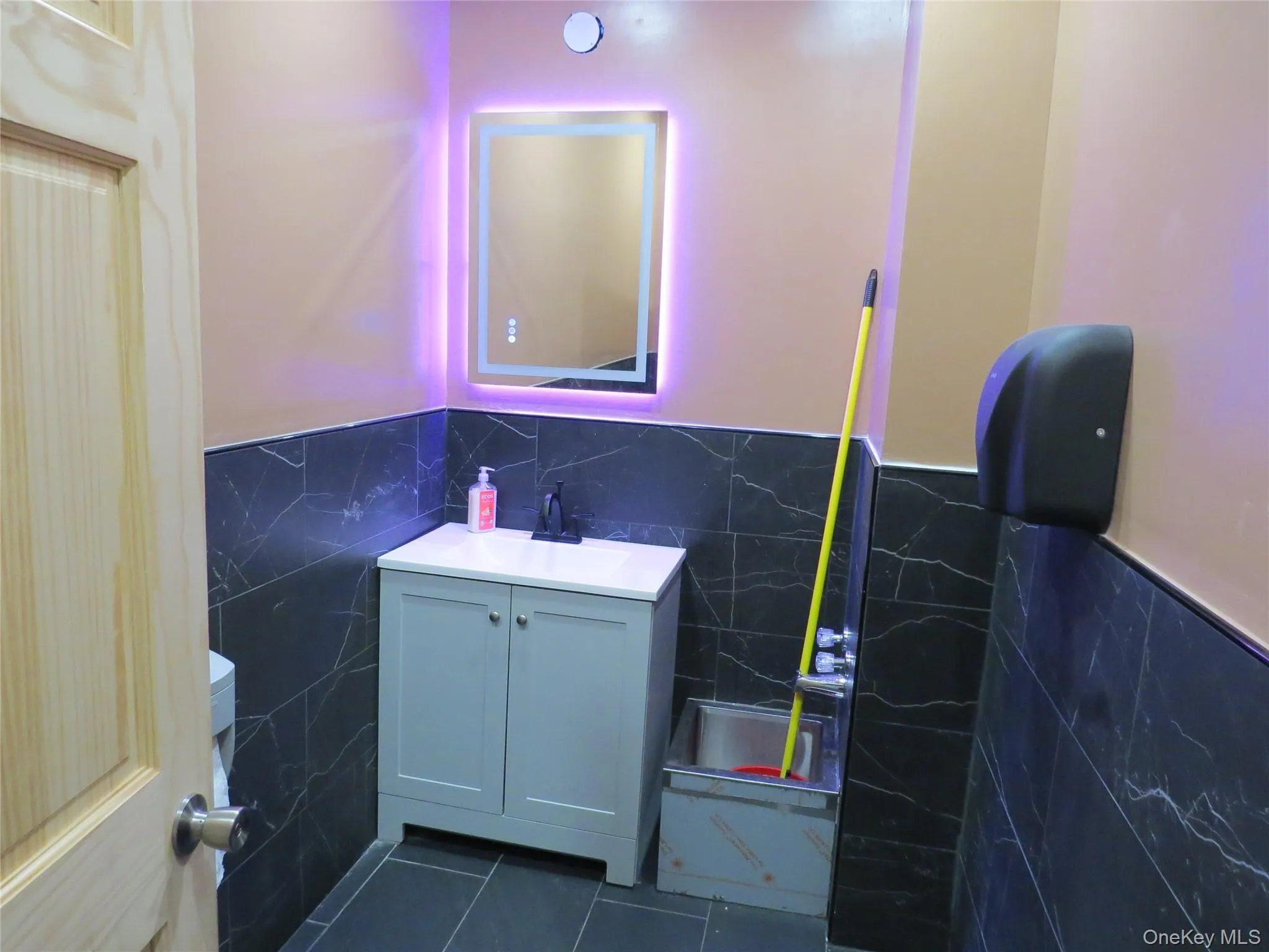 Bathroom featuring tile walls, vanity, dark tile patterned floors Bathroom featuring tile walls, vanity, dark tile patterned floors