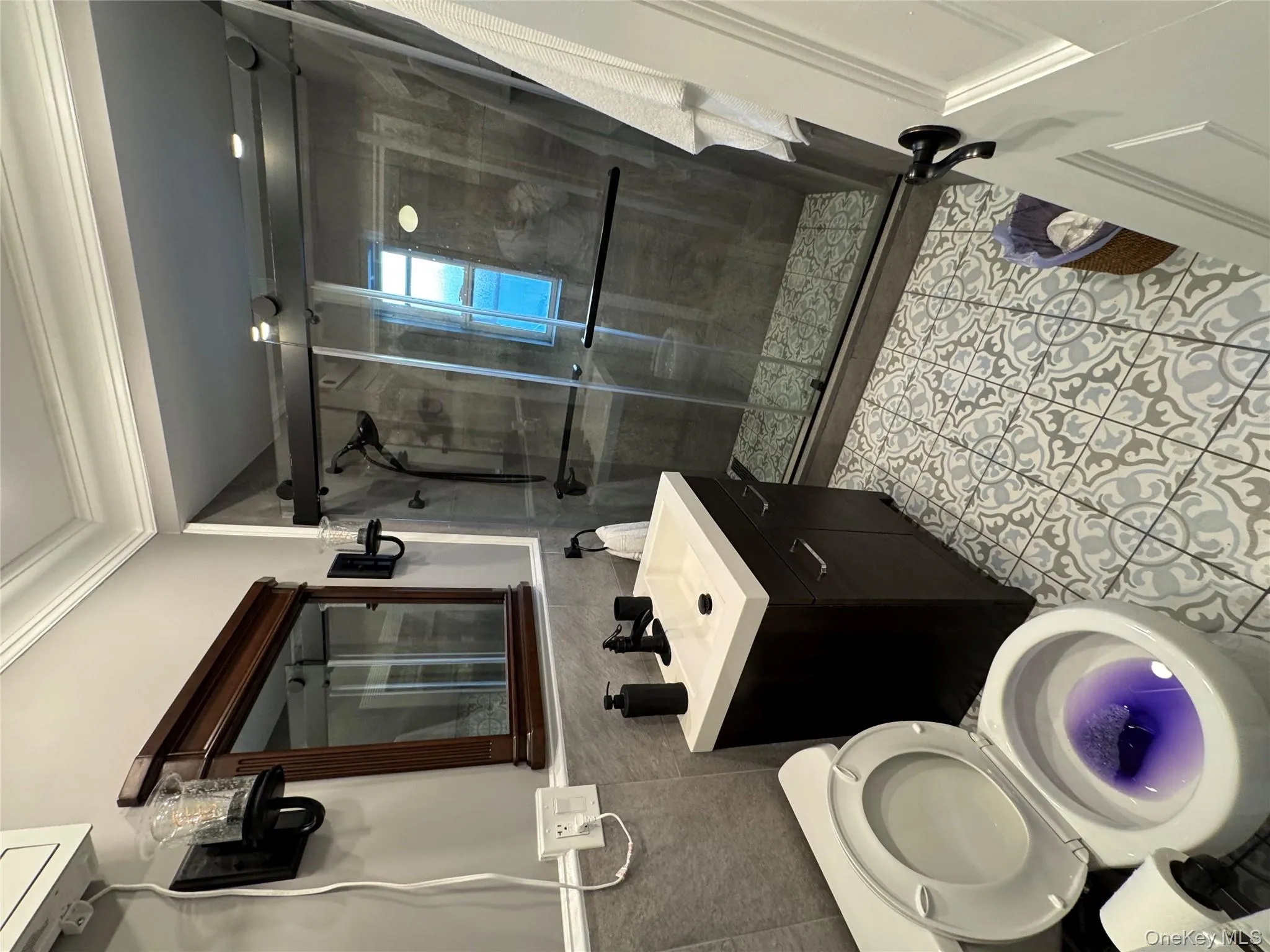 Bathroom featuring tile walls, light tile patterned flooring, a stall shower, vanity, and crown molding Bathroom featuring tile walls, light tile patterned flooring, a stall shower, vanity, and crown molding