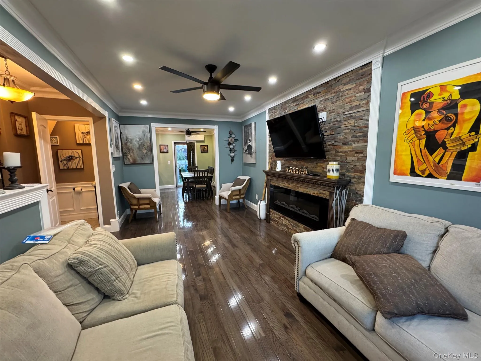 Living room featuring a fireplace, ornamental molding, ceiling fan, dark wood-style flooring, and recessed lighting Living room featuring a fireplace, ornamental molding, ceiling fan, dark wood-style flooring, and recessed lighting