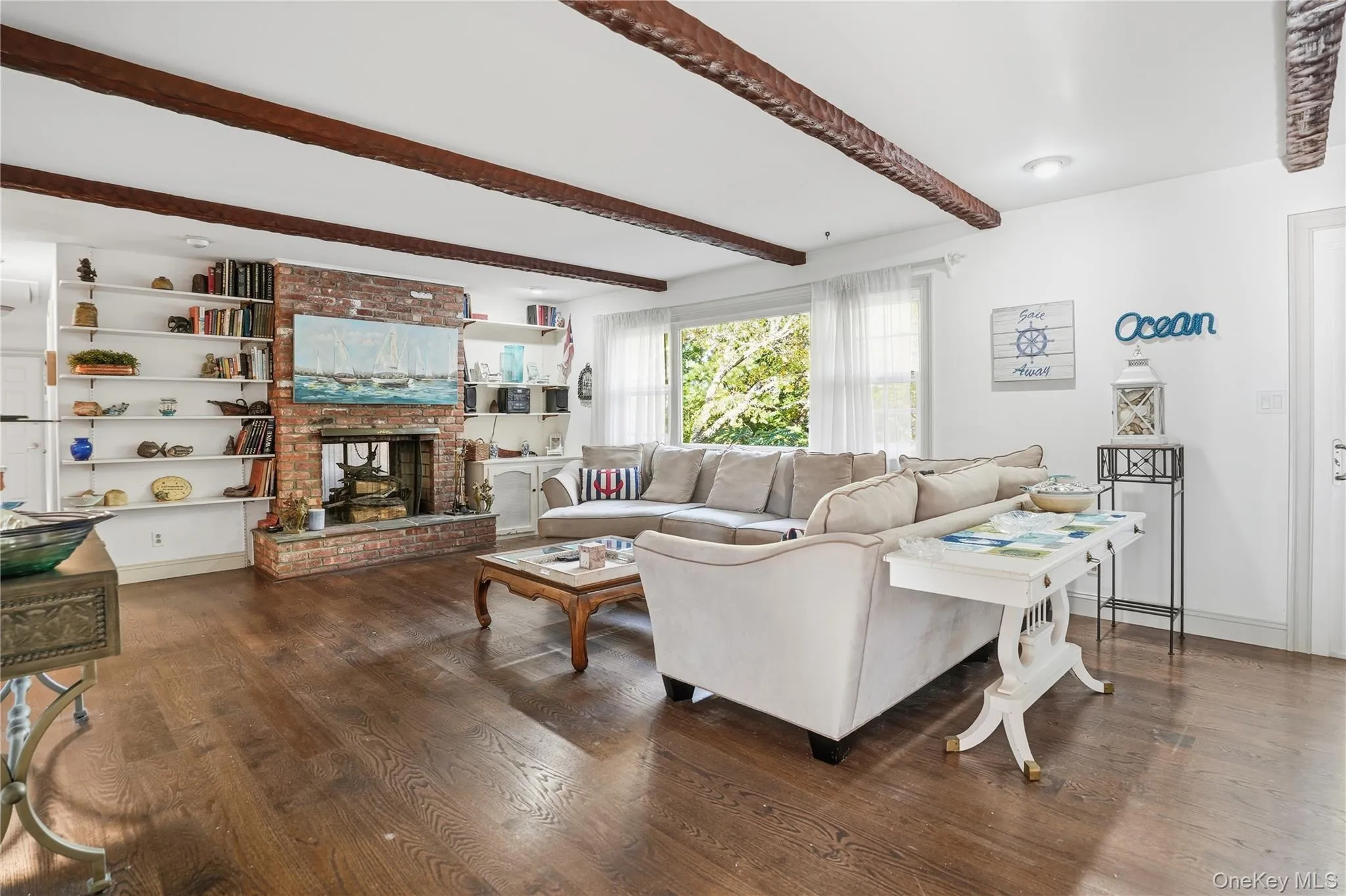 Living room featuring beam ceiling, dark wood-style flooring, and a fireplace Living room featuring beam ceiling, dark wood-style flooring, and a fireplace