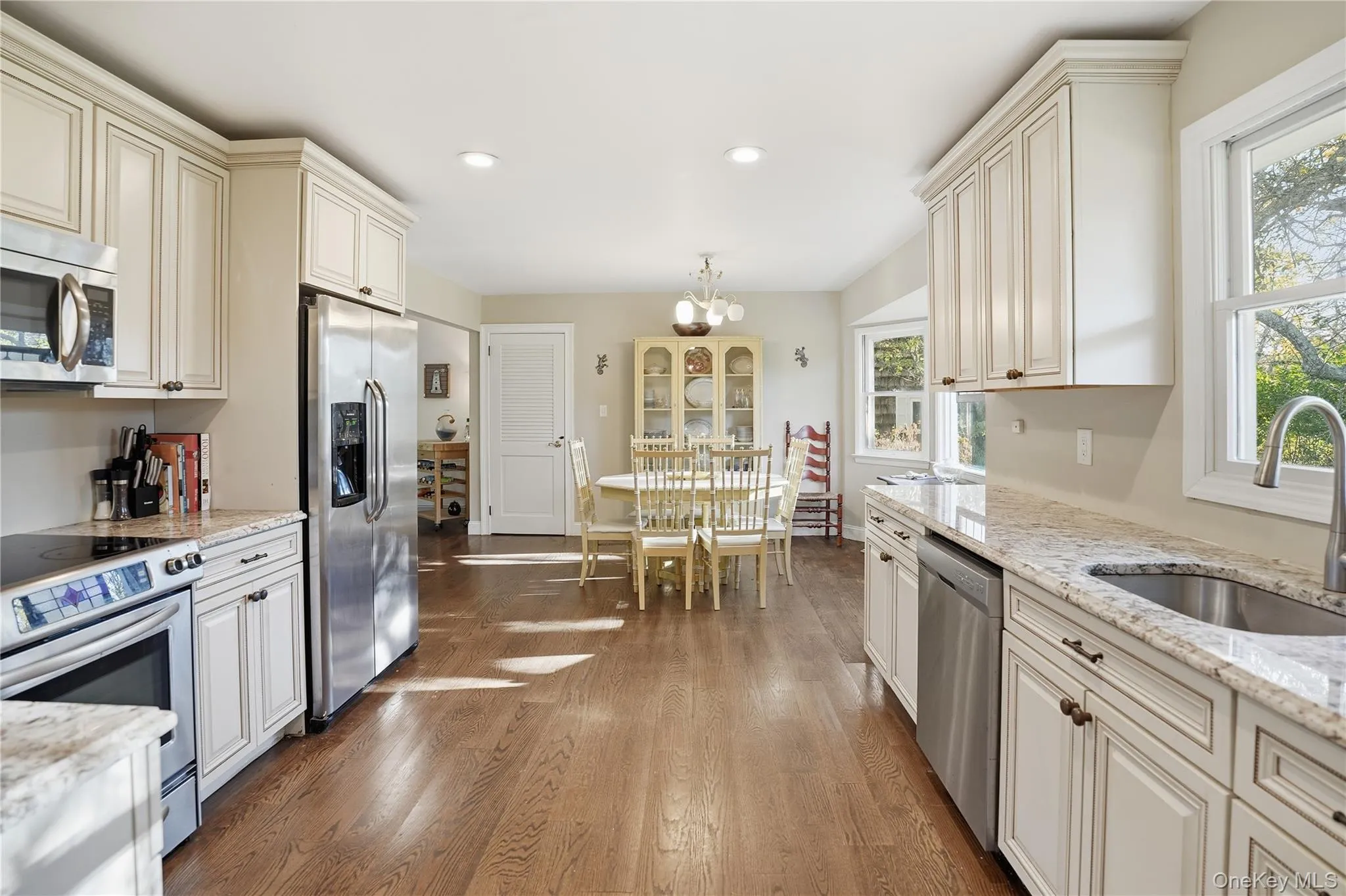 Kitchen featuring stainless steel appliances, light stone counters, a chandelier, hanging light fixtures, and recessed lighting Kitchen featuring stainless steel appliances, light stone counters, a chandelier, hanging light fixtures, and recessed lighting