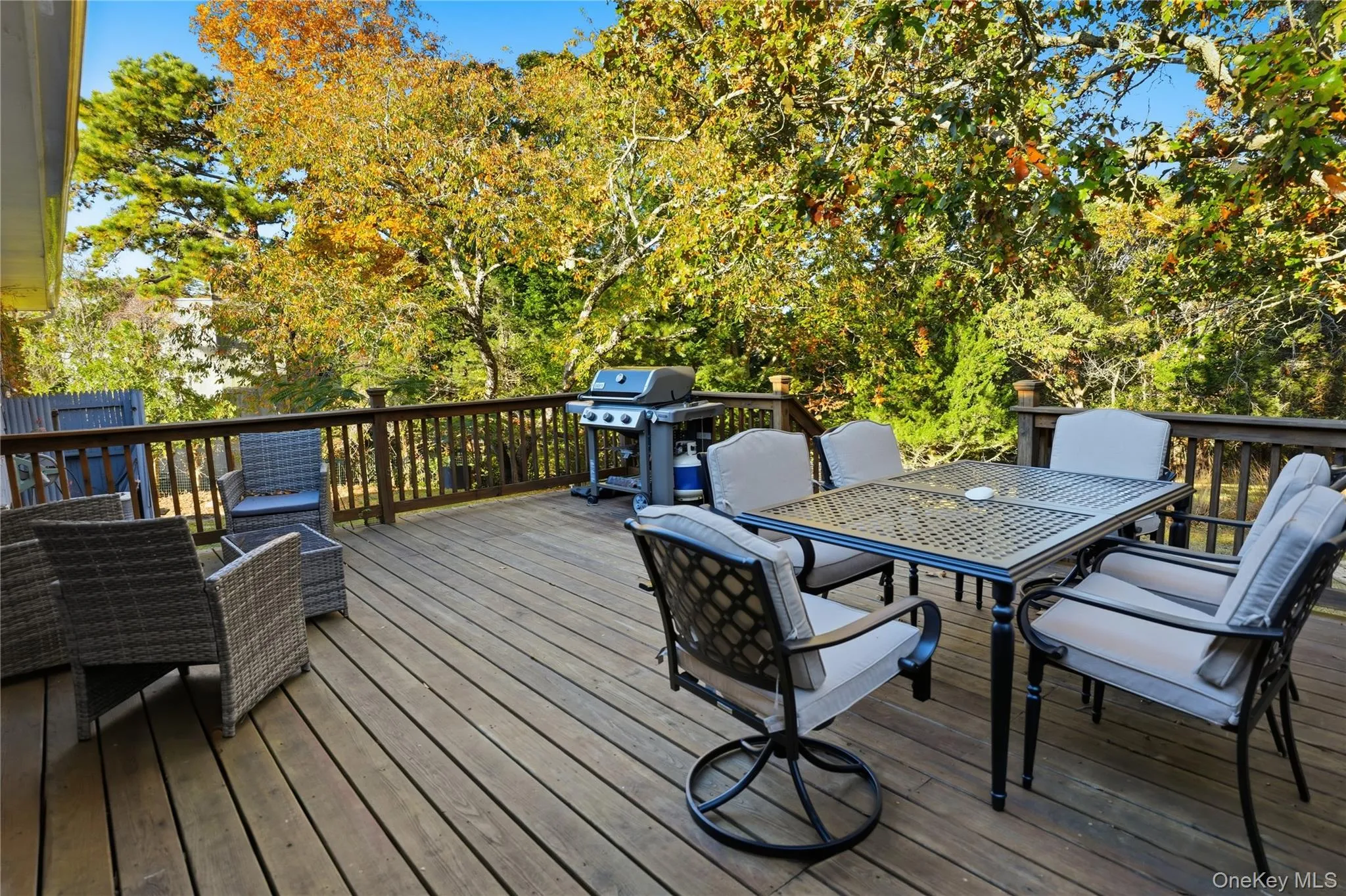 Wooden terrace featuring outdoor dining area, a grill, and view of scattered trees Wooden terrace featuring outdoor dining area, a grill, and view of scattered trees