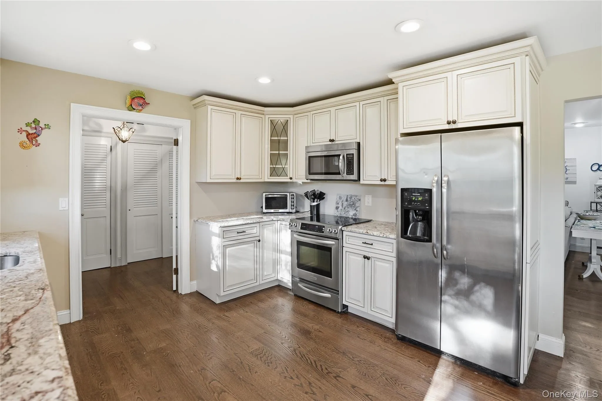 Kitchen with appliances with stainless steel finishes, dark wood finished floors, light stone counters, glass insert cabinets, and recessed lighting Kitchen with appliances with stainless steel finishes, dark wood finished floors, light stone counters, glass insert cabinets, and recessed lighting