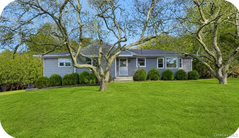 Ranch-style residence featuring grey siding, a dark roof, and white window frames