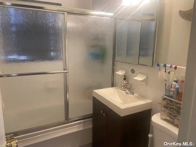Bathroom with vanity, combined bath / shower with glass door, and decorative backsplash Bathroom with vanity, combined bath / shower with glass door, and decorative backsplash