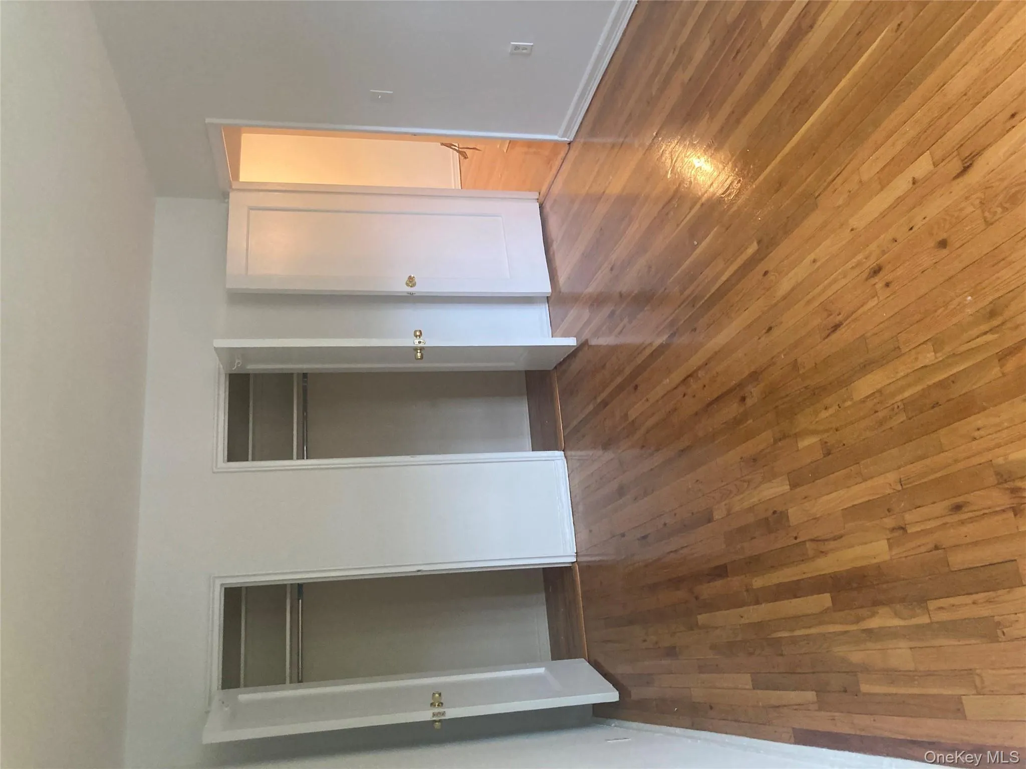 Unfurnished bedroom with hardwood floors and multiple closets Unfurnished bedroom with hardwood floors and multiple closets