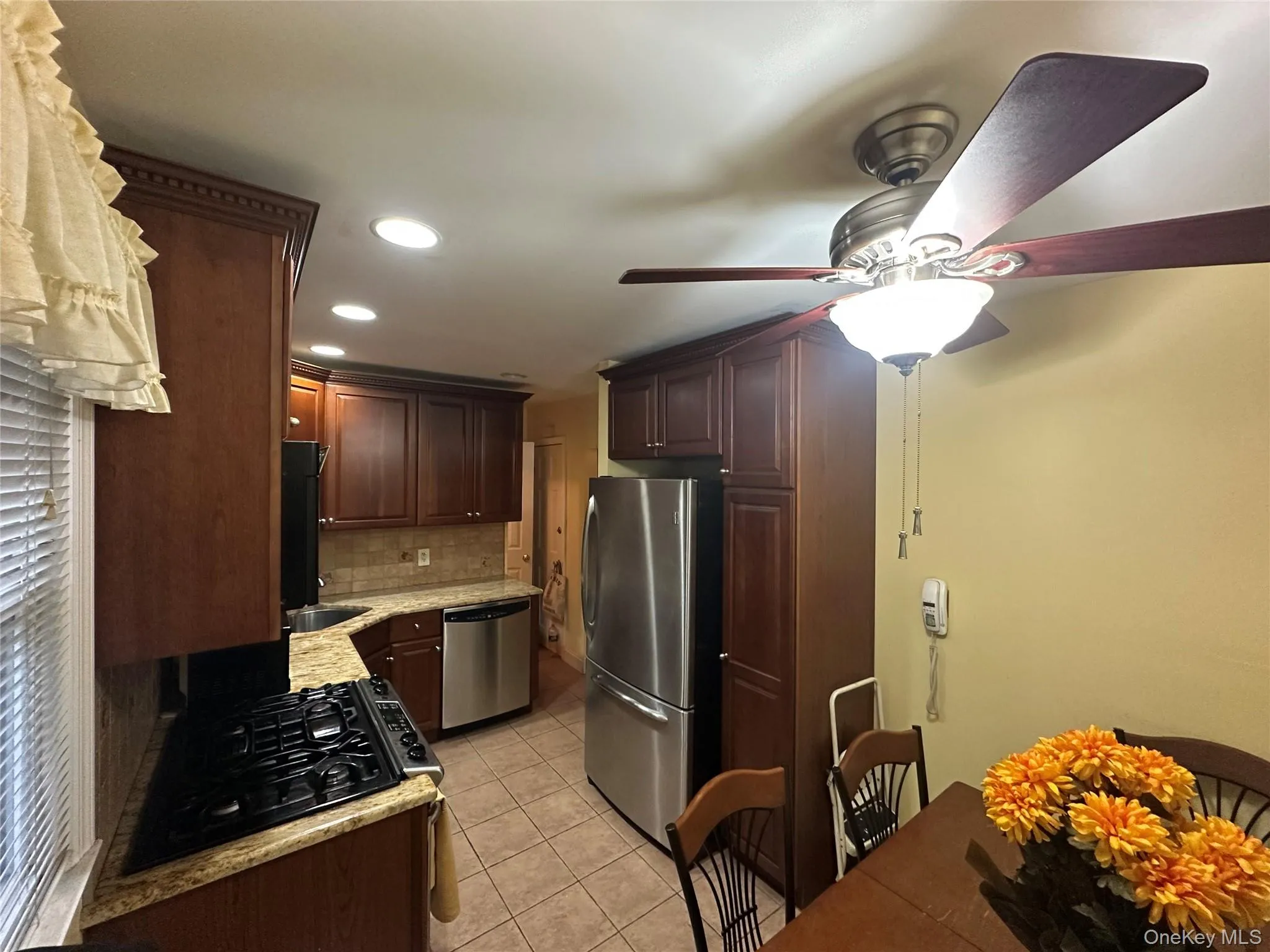 Kitchen with light tile patterned floors, tasteful backsplash, black appliances, recessed lighting, and dark brown cabinets Kitchen with light tile patterned floors, tasteful backsplash, black appliances, recessed lighting, and dark brown cabinets