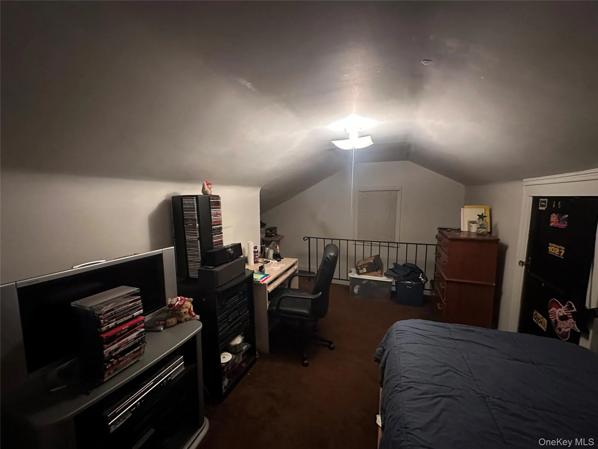 Bedroom featuring dark colored carpet, lofted ceiling, and an office area Bedroom featuring dark colored carpet, lofted ceiling, and an office area