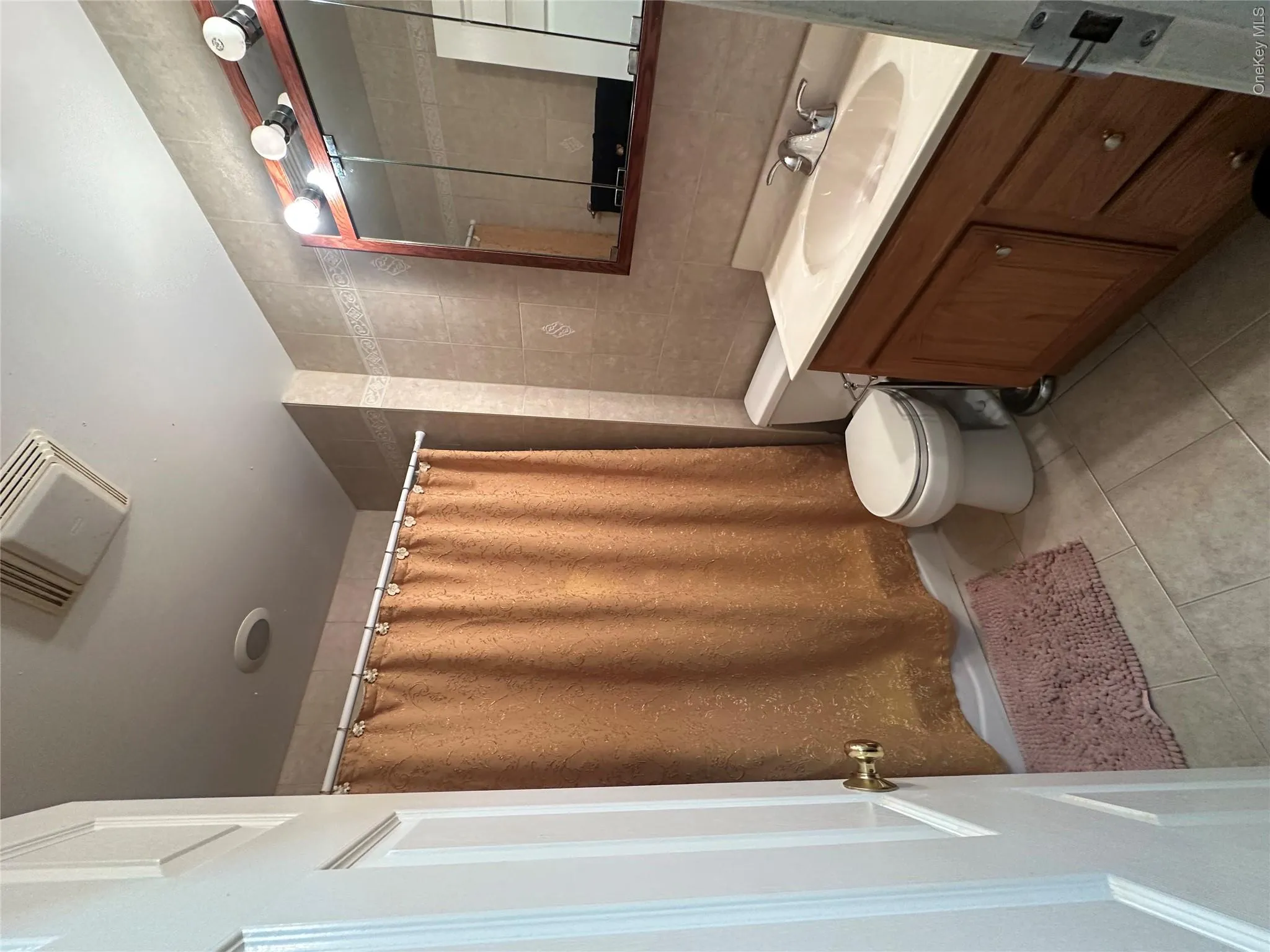 Full bathroom featuring tile walls, light tile patterned flooring, vanity, and shower / bath combination with curtain Full bathroom featuring tile walls, light tile patterned flooring, vanity, and shower / bath combination with curtain