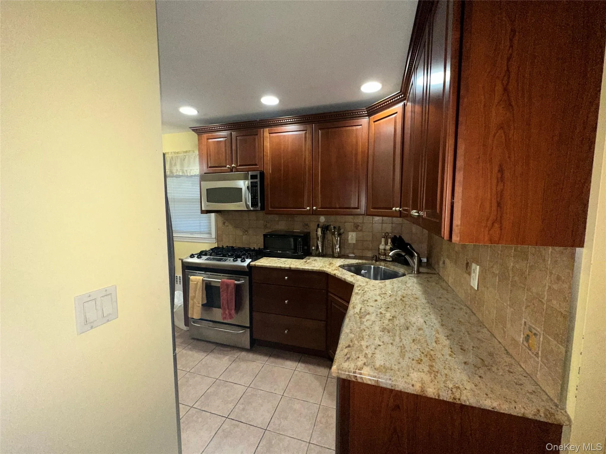 Kitchen featuring backsplash, stainless steel appliances, light tile patterned floors, light stone counters, and recessed lighting Kitchen featuring backsplash, stainless steel appliances, light tile patterned floors, light stone counters, and recessed lighting