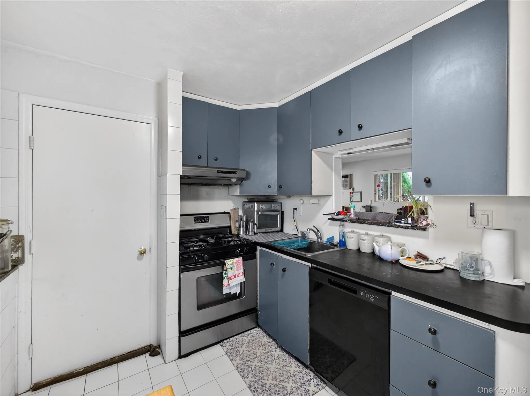 Kitchen with dark countertops, black dishwasher, gas range, and blue cabinets Kitchen with dark countertops, black dishwasher, gas range, and blue cabinets