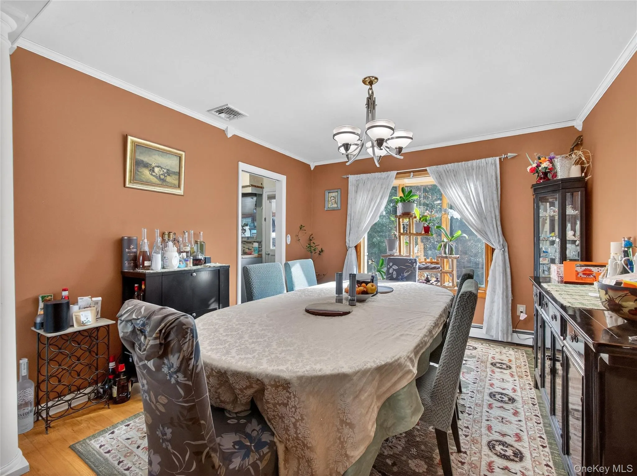 Dining area with crown molding, a chandelier, light wood finished floors, and baseboard heating Dining area with crown molding, a chandelier, light wood finished floors, and baseboard heating