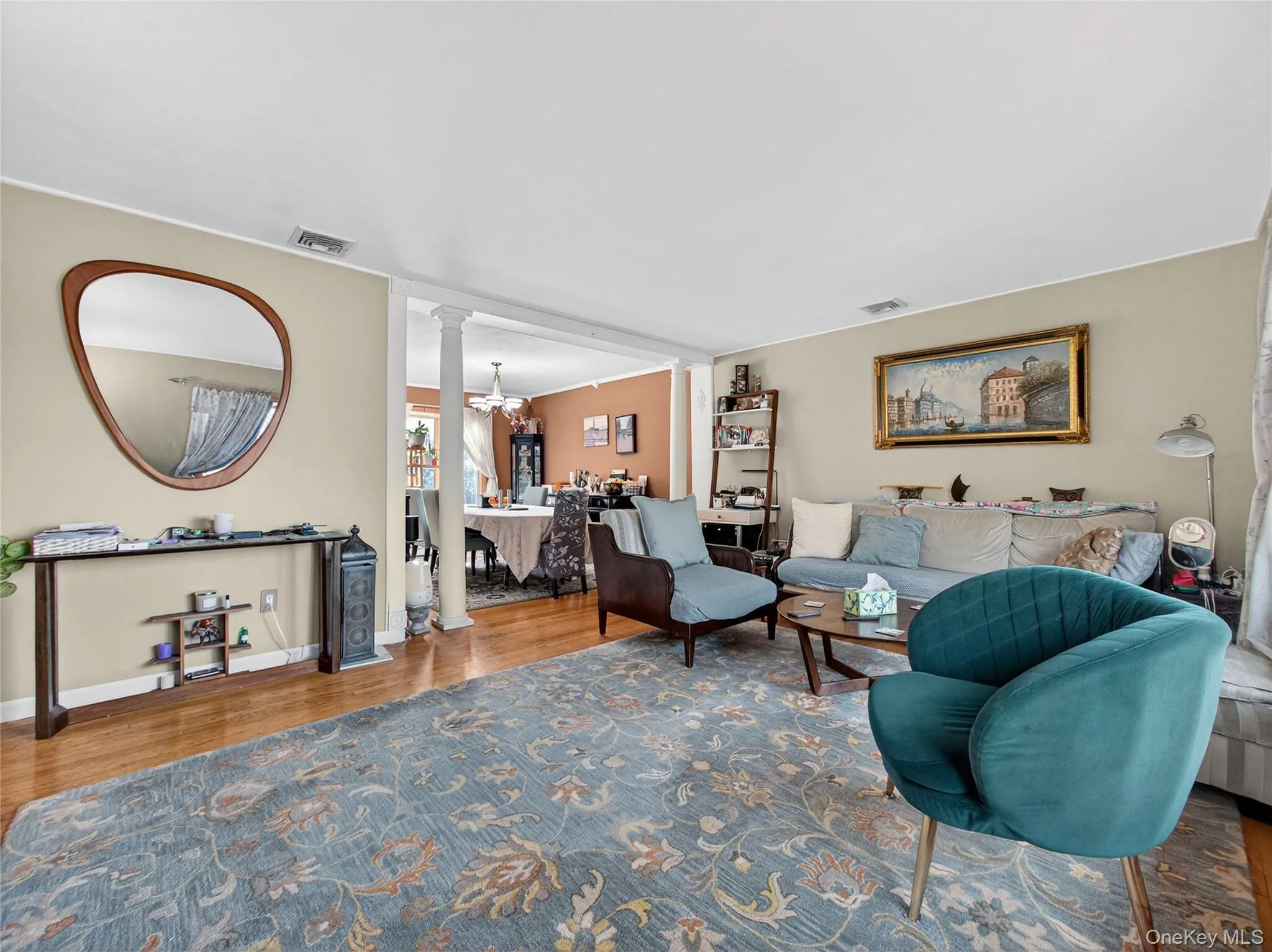 Living room featuring decorative columns, wood finished floors, and a chandelier Living room featuring decorative columns, wood finished floors, and a chandelier