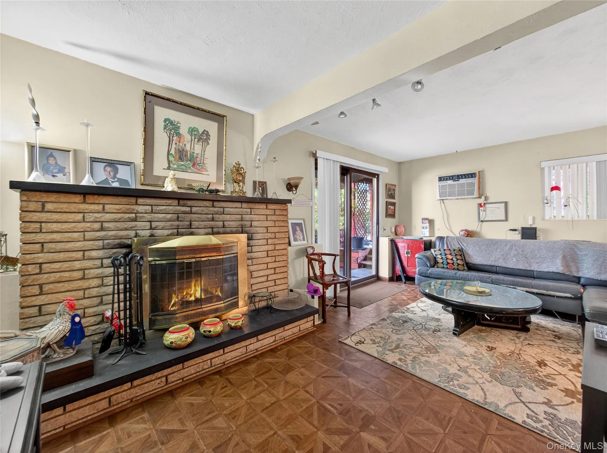 Living room featuring a brick fireplace and an AC wall unit Living room featuring a brick fireplace and an AC wall unit
