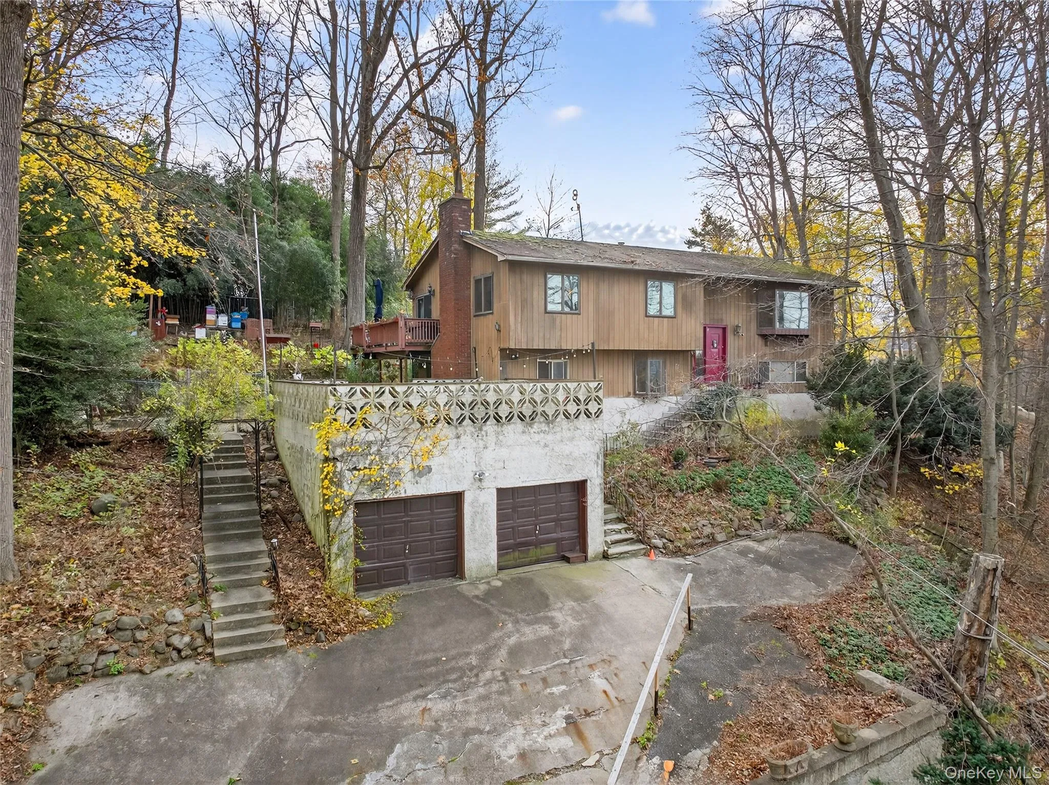 View of front facade with stairway, a chimney, driveway, and an attached garage View of front facade with stairway, a chimney, driveway, and an attached garage